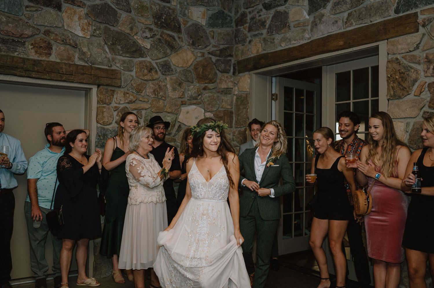 Wedding party dancing and celebrating in a stone-walled venue.