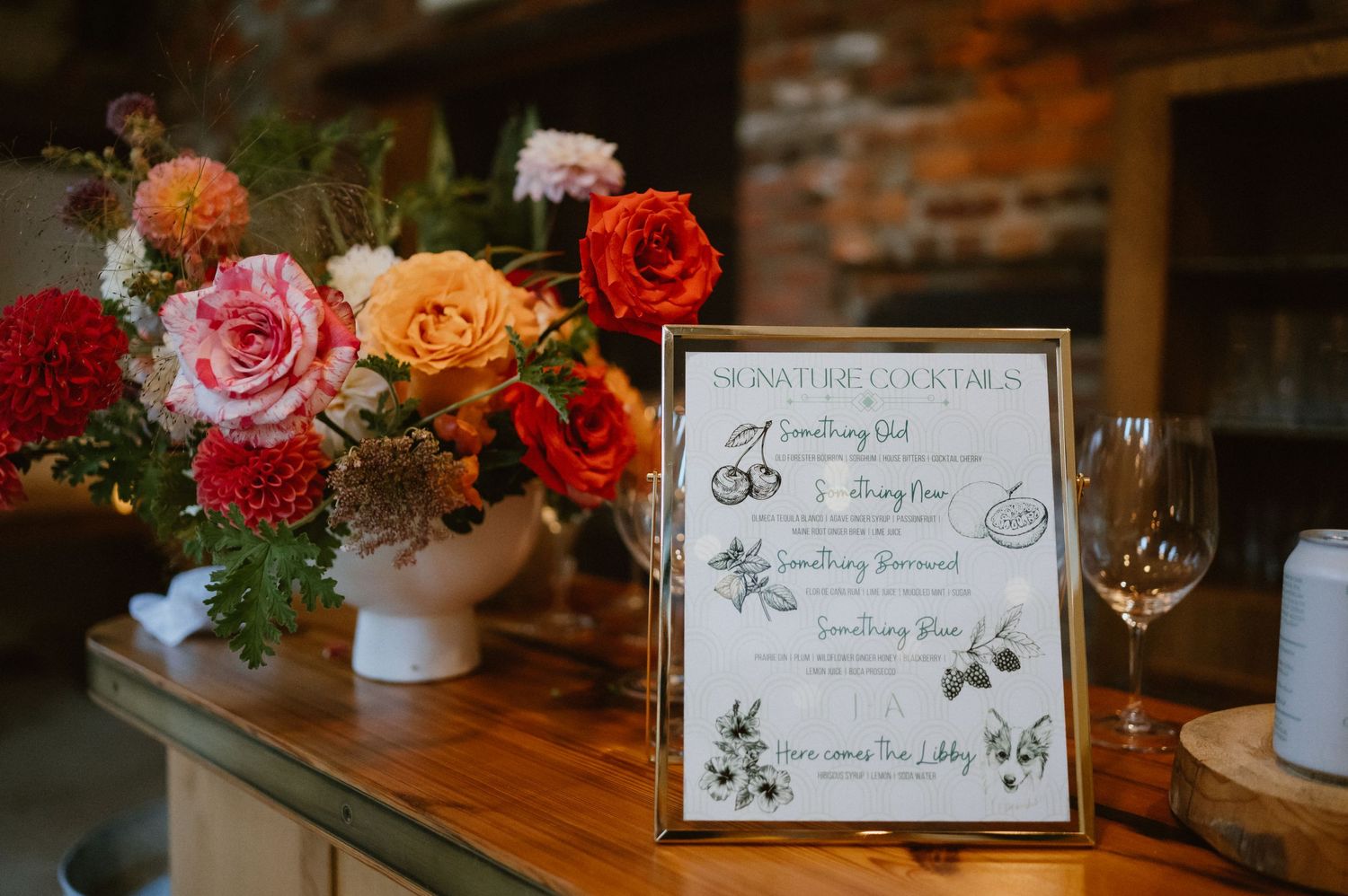 A wedding menu card displayed next to a vibrant floral arrangement on wooden table.