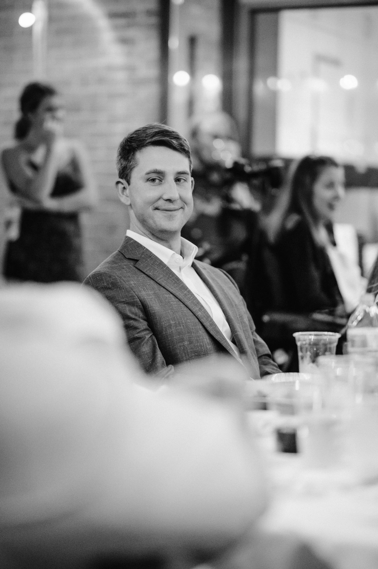 Black and white portrait of guest in formal attire at wedding reception.