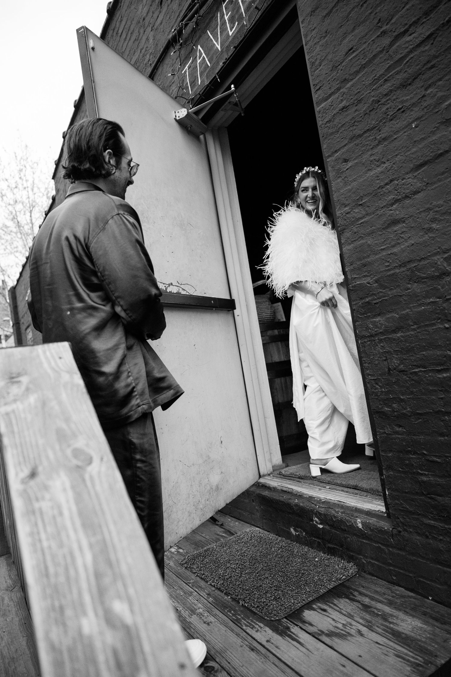 People walking through a doorway with black painted brick walls.