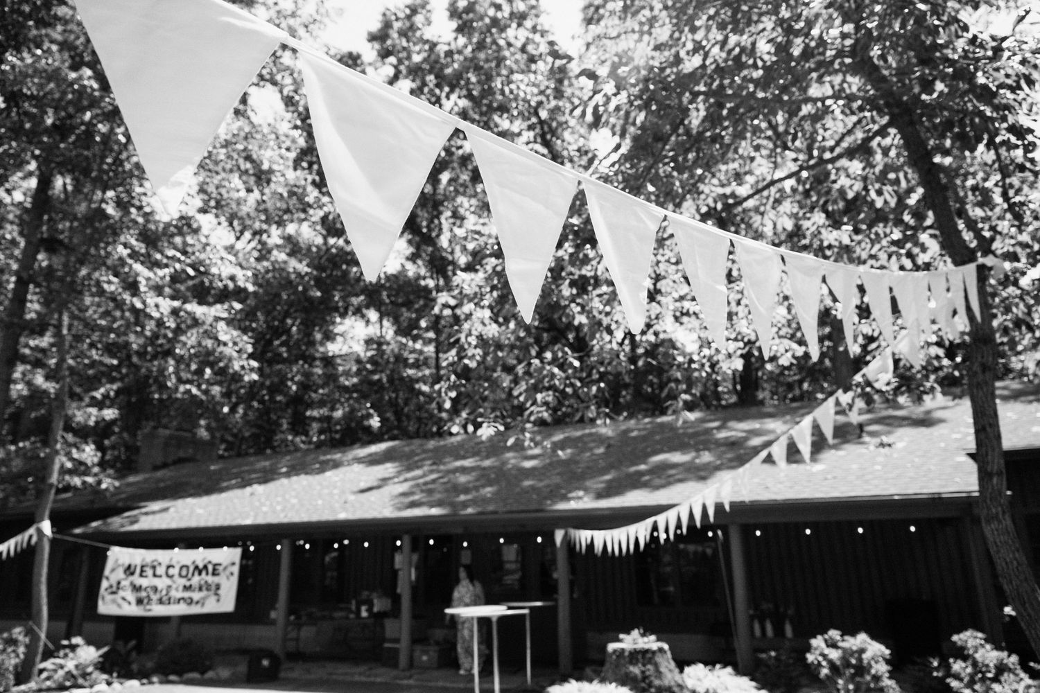 Black and white photo of white bunting decorating an outdoor wedding venue.