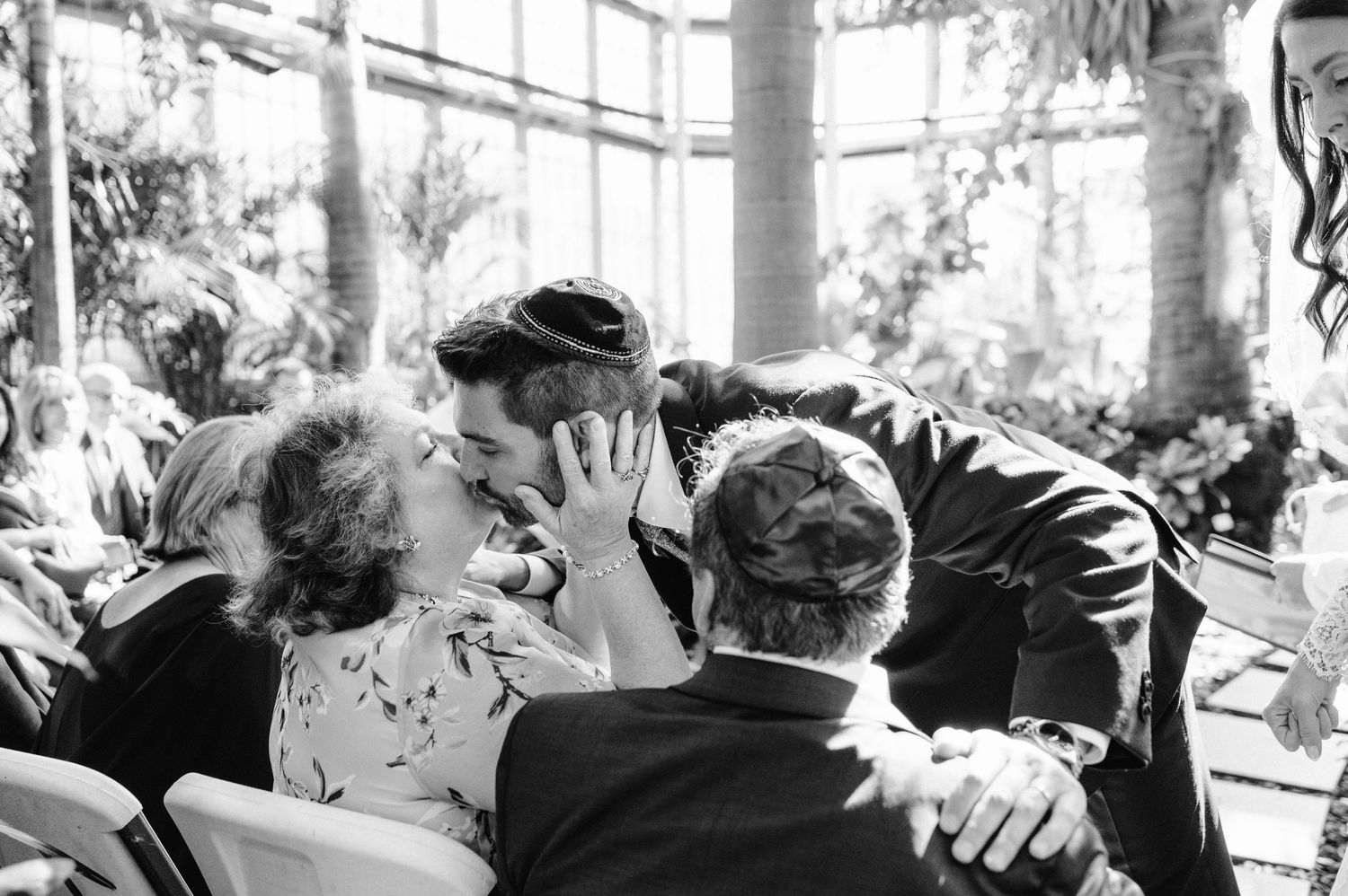 Black and white candid moment of emotional embraces during wedding celebration.
