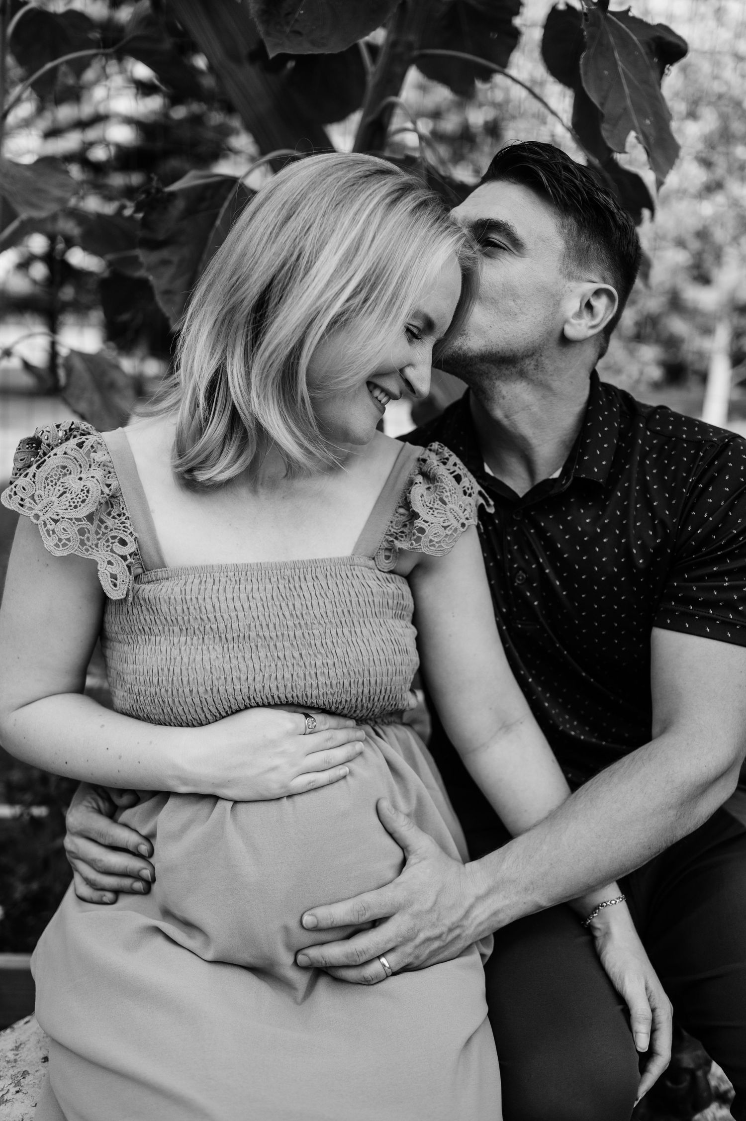 An intimate black and white portrait of a couple sharing a tender moment in a garden.