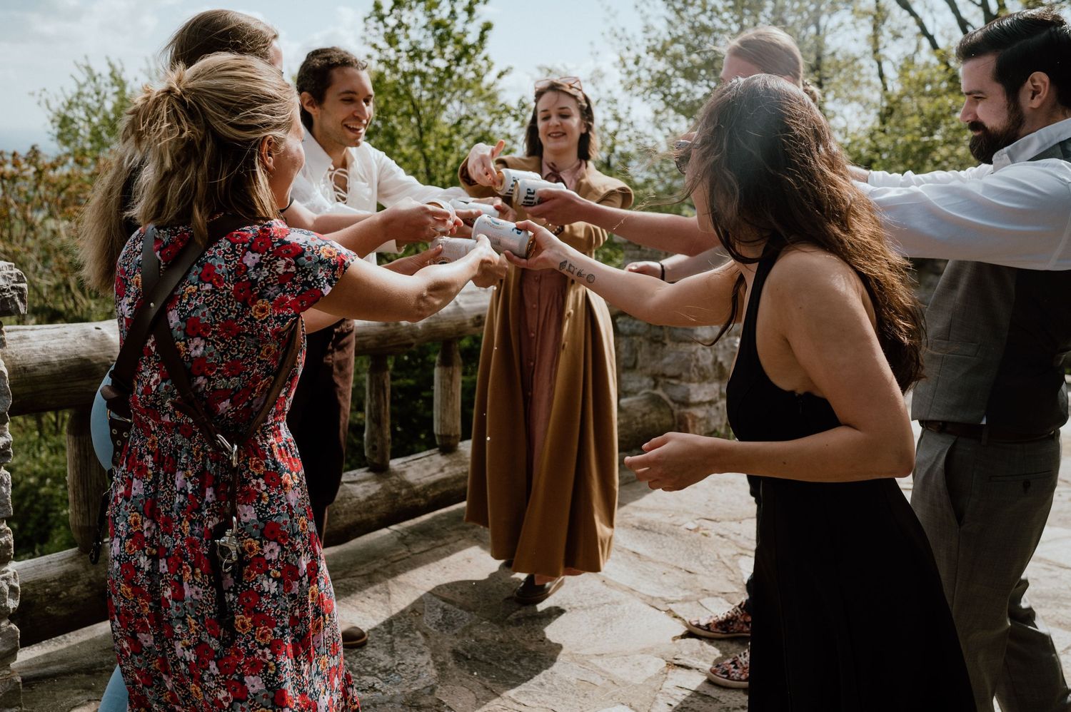 A group of friends toasting with drinks on an outdoor viewing deck.