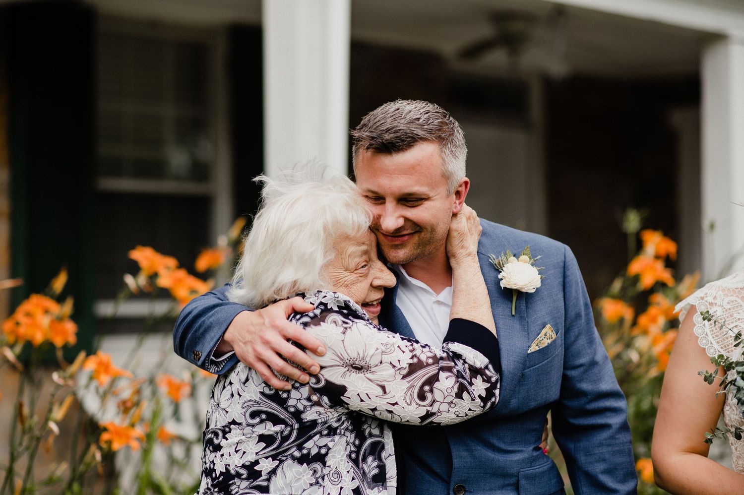 An emotional embrace captured during a wedding celebration surrounded by bright orange daylilies.