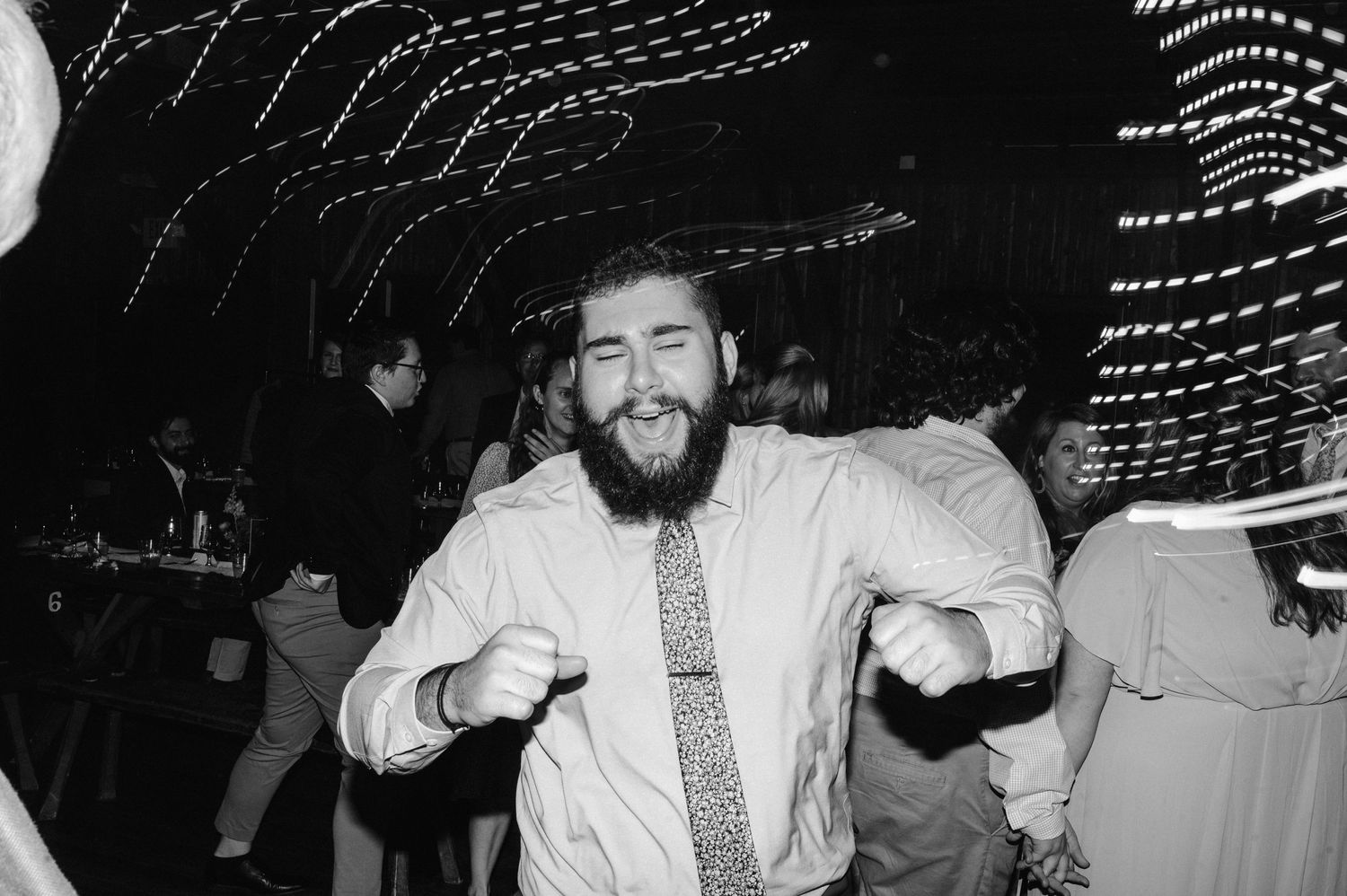 Guest dancing energetically at wedding reception with light trails in background.