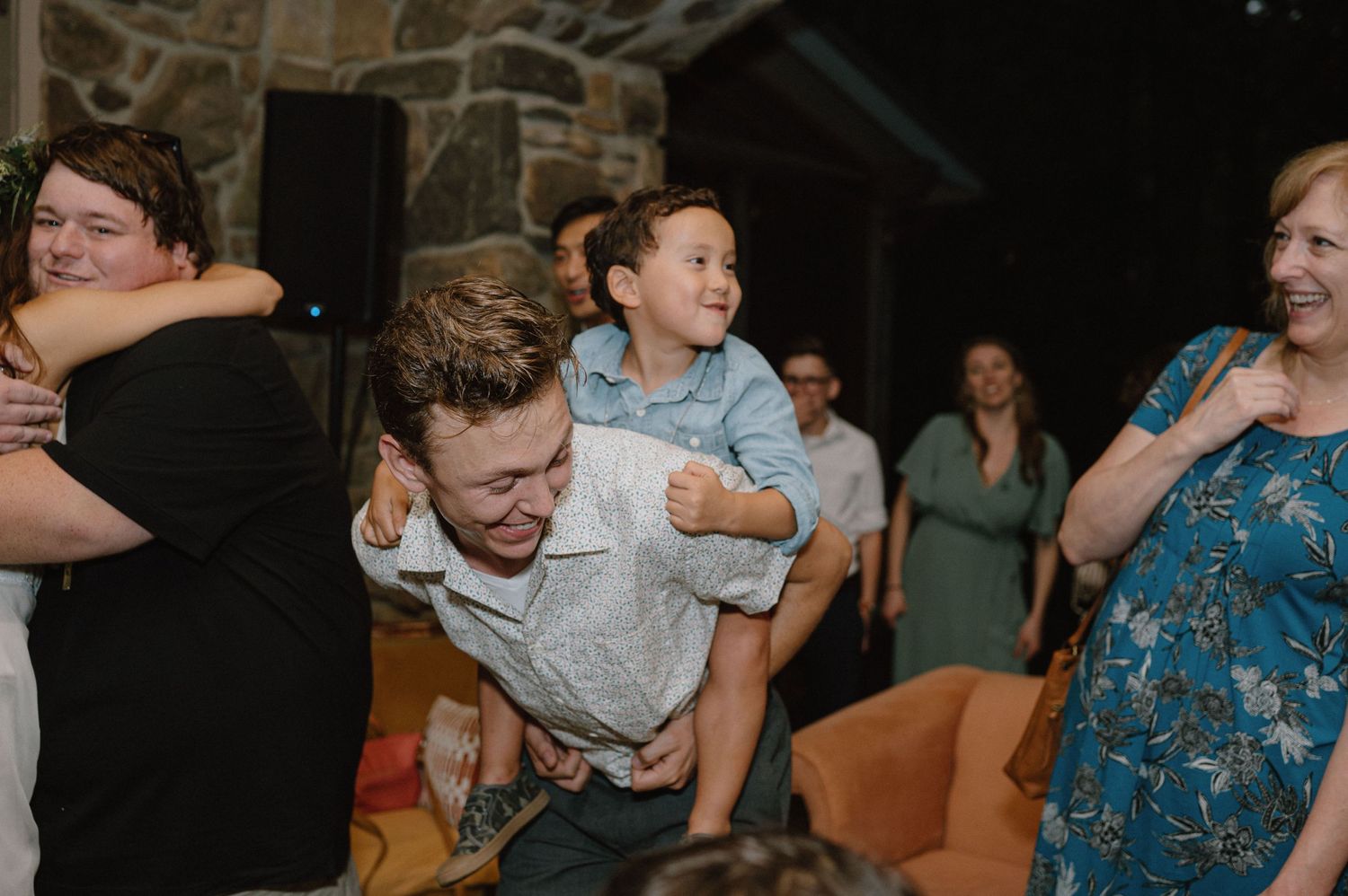Guests laugh and embrace during lively wedding reception celebrations.