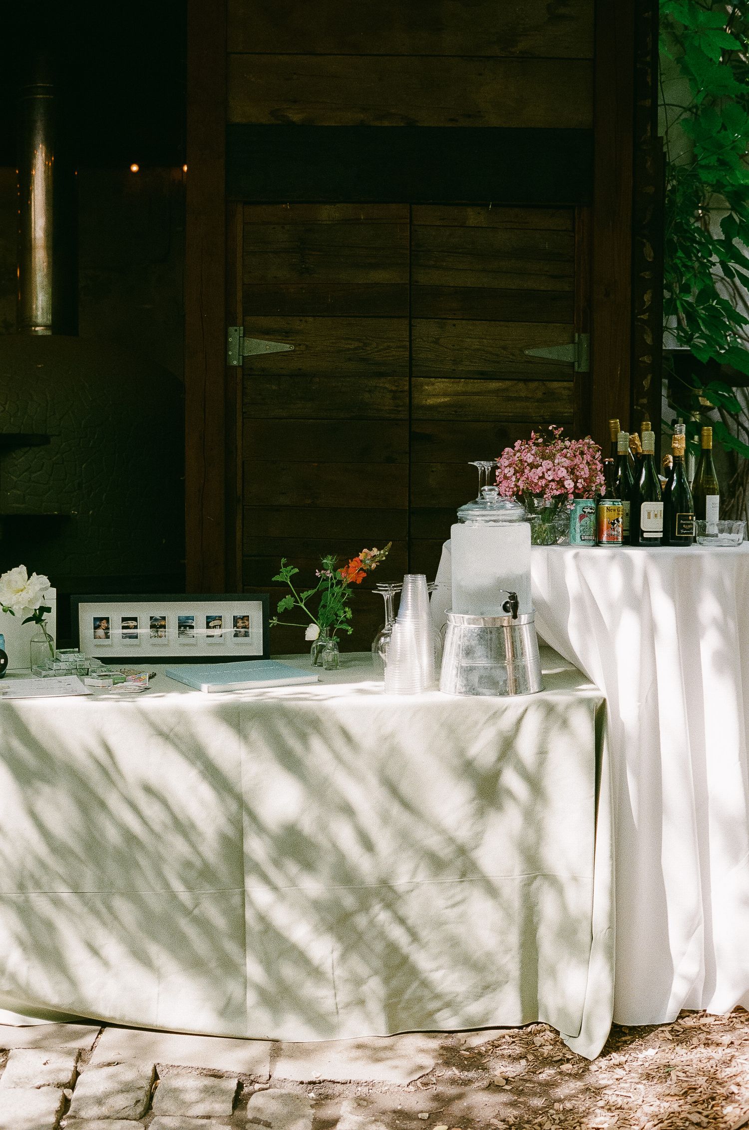 White tablecloths and decor cast dappled shadows in an outdoor event setting.