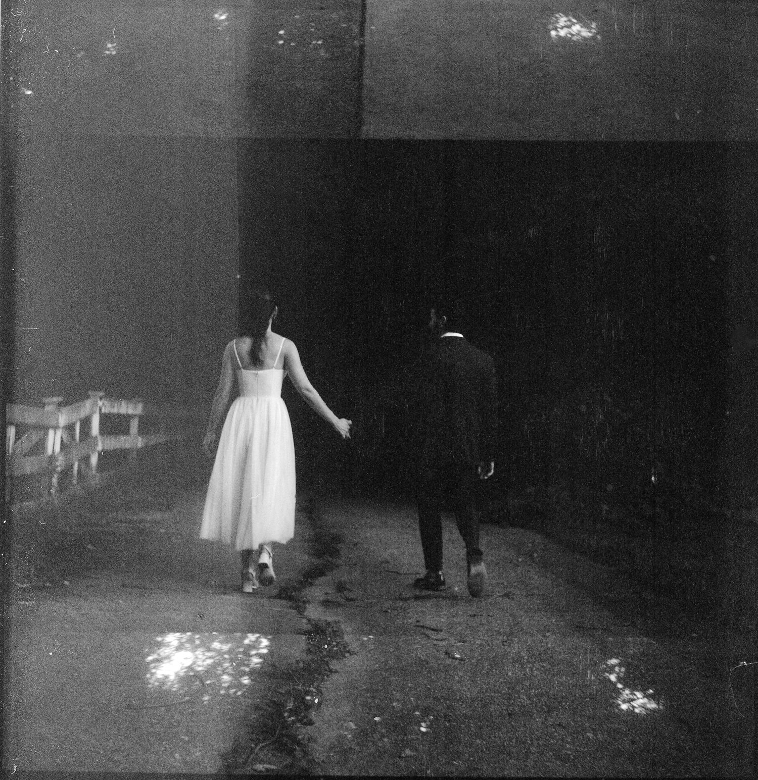 Black and white artistic photos of a white dress moving on a dark ground creating ethereal movement.