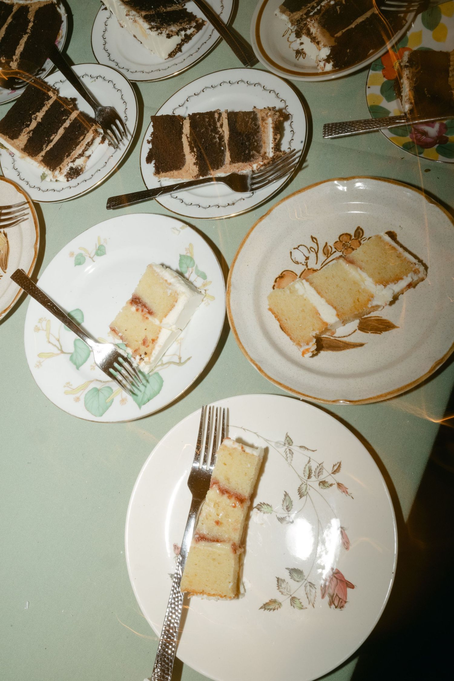 Multiple plates of layered wedding cake slices displayed on decorative china with floral patterns.