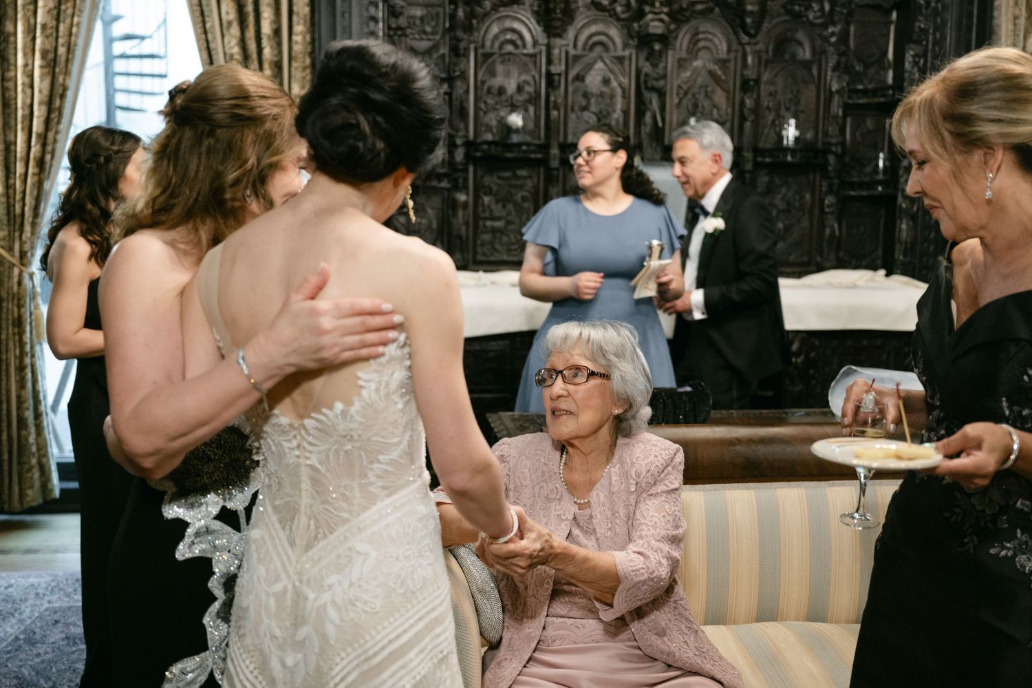 Wedding guests gathered around in formal attire during an indoor celebration.
