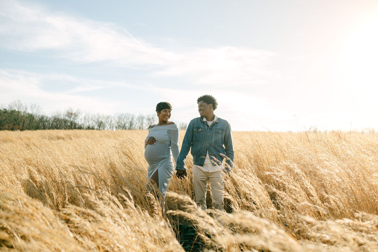 pregnant women holding hands with husband in field in maryland