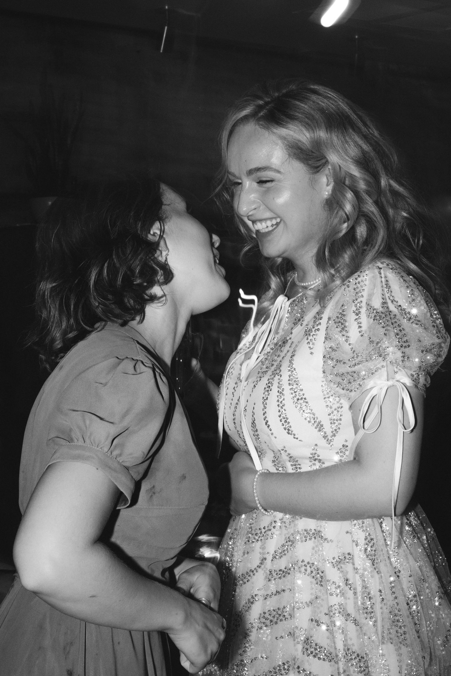 Two people sharing a joyful moment at a party captured in black and white photography.