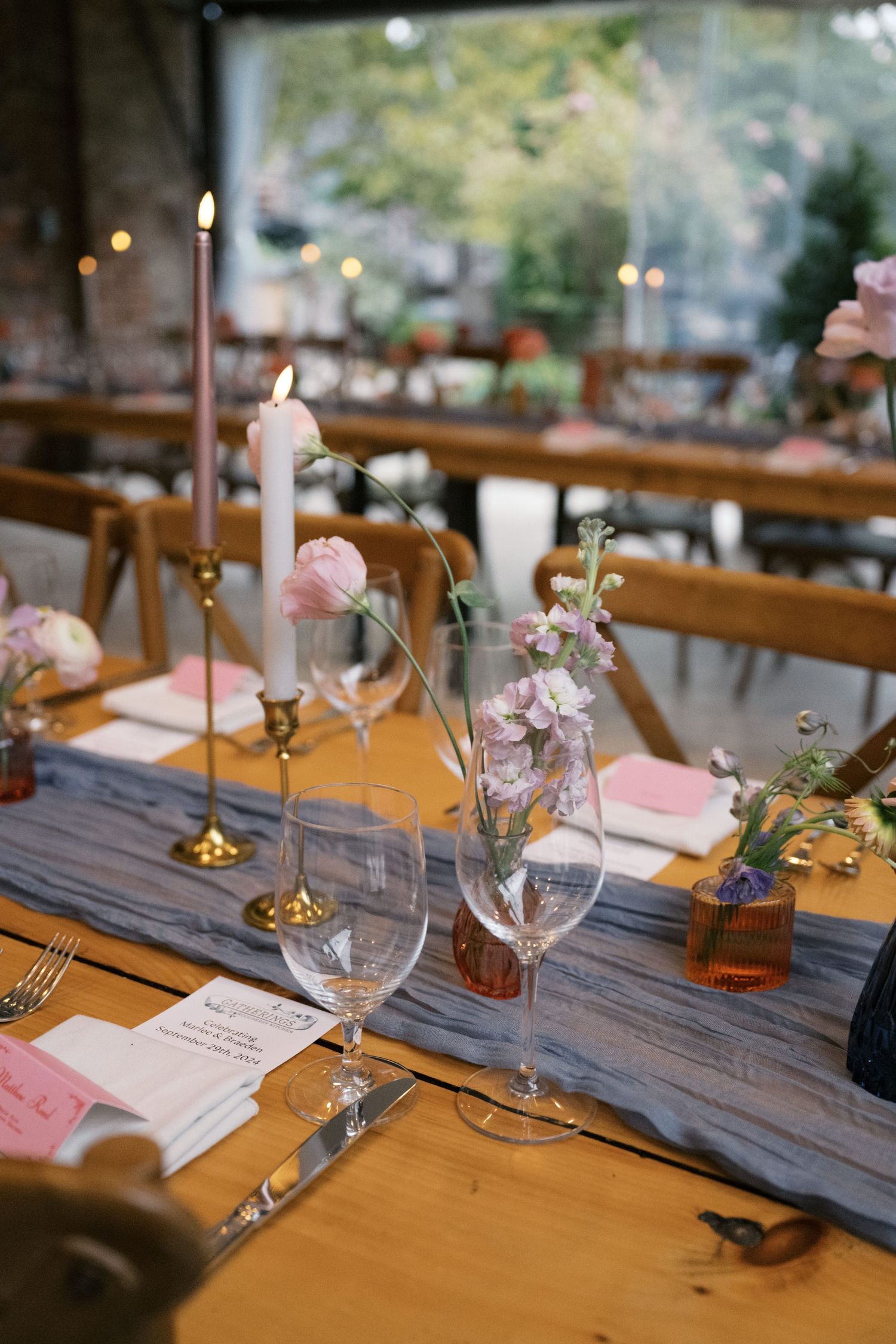Elegant table setting with candles, wine glasses and delicate pink floral arrangements.