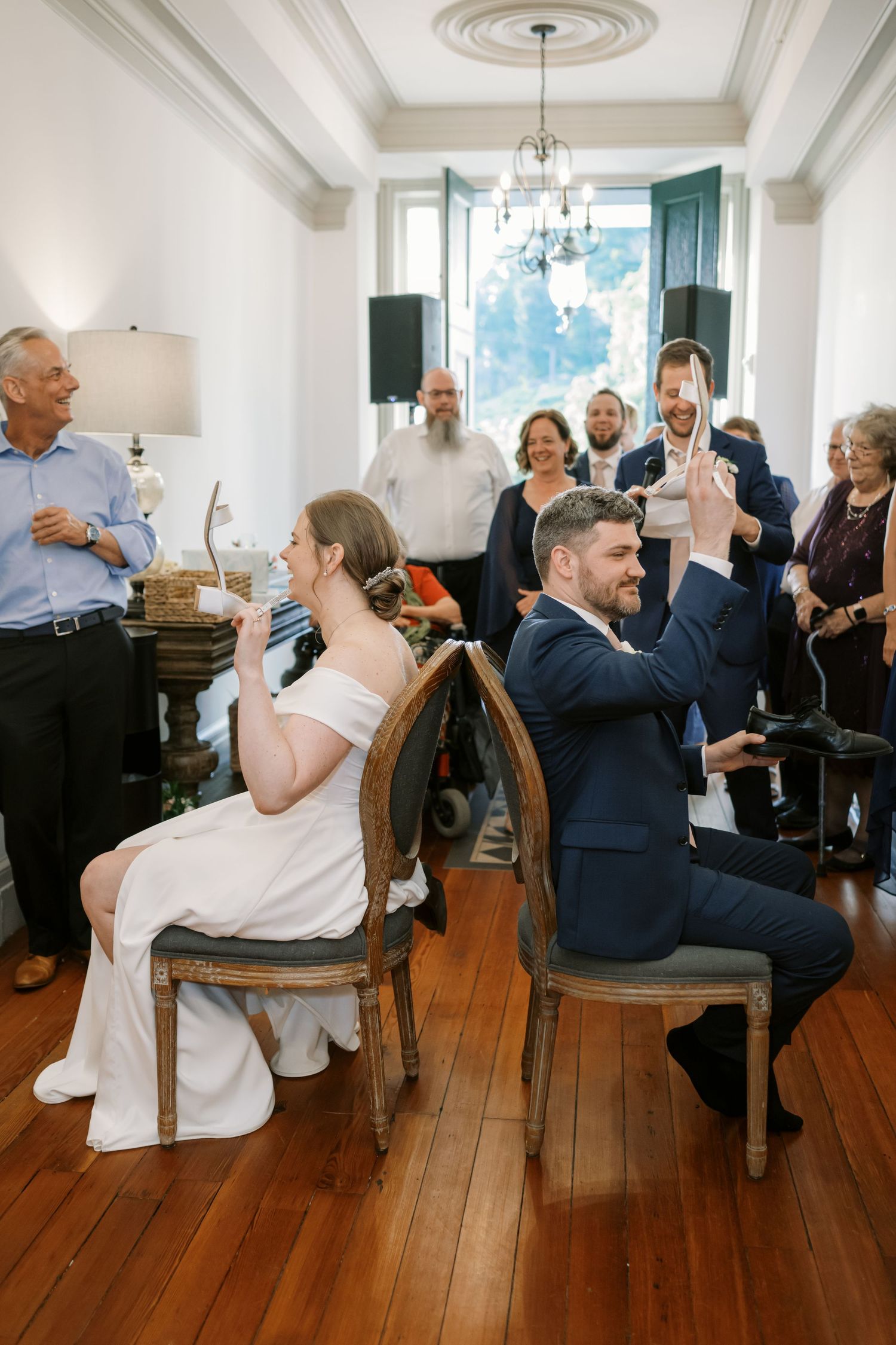 Wedding guests playing a fun game in an elegant room with hardwood floors and chandelier.
