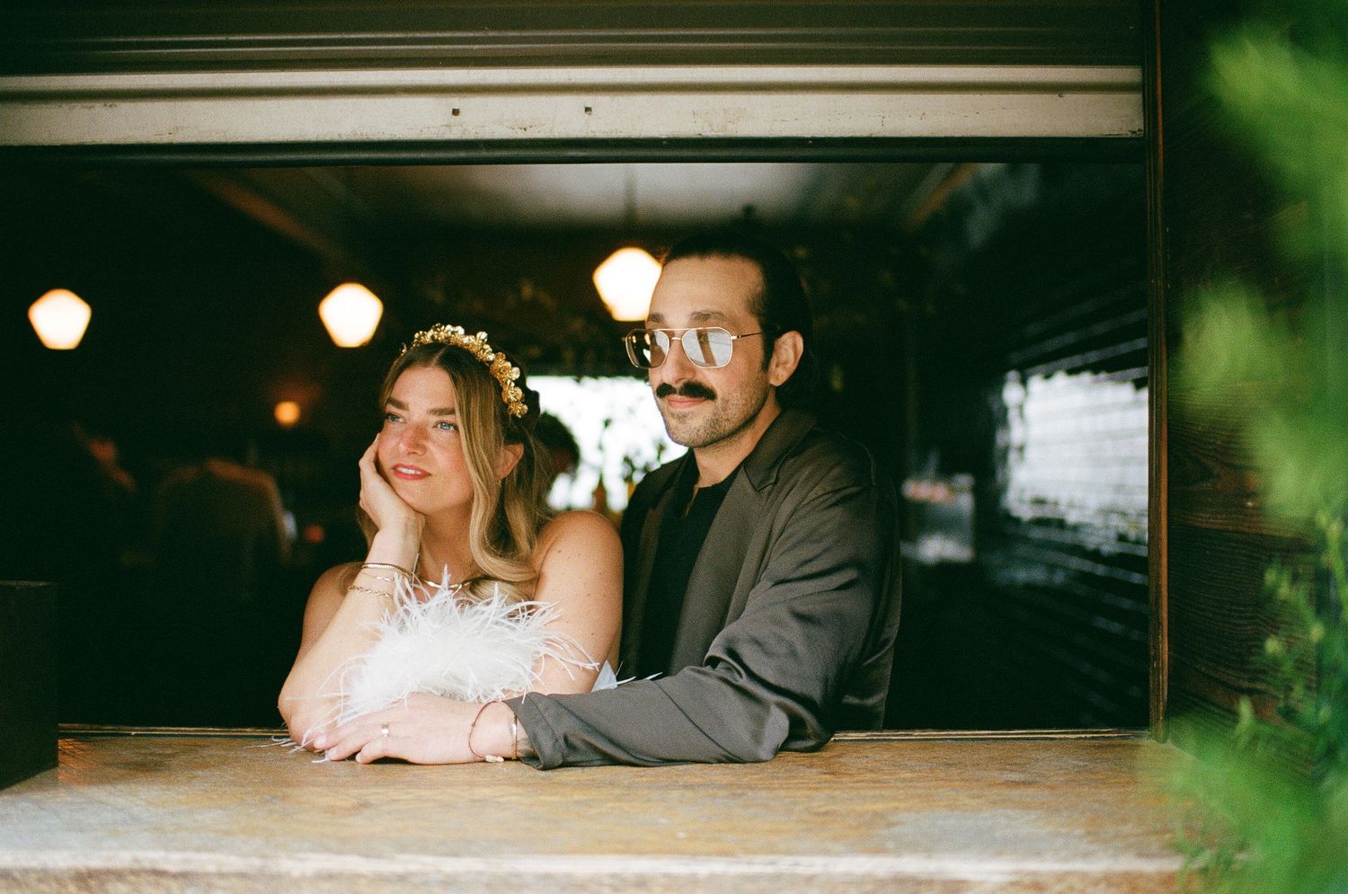 A couple shares a romantic moment at a venue with glowing lights and greenery in the background at Fadensonnen in Baltimore