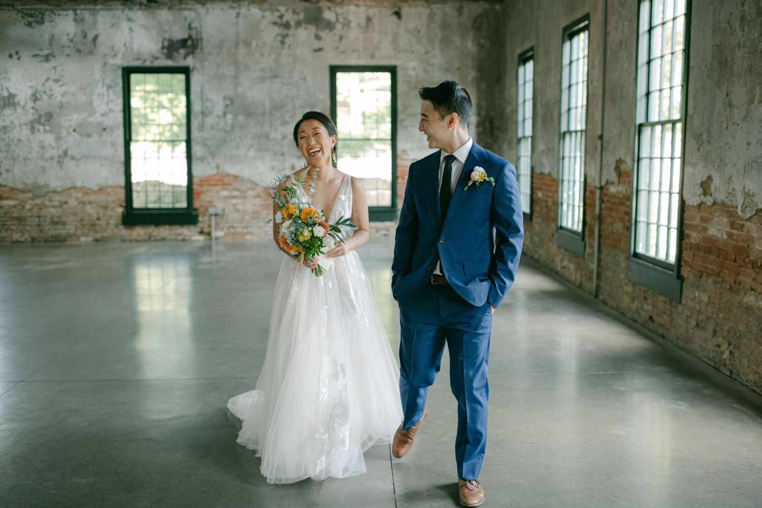 bride and groom walk together laughing