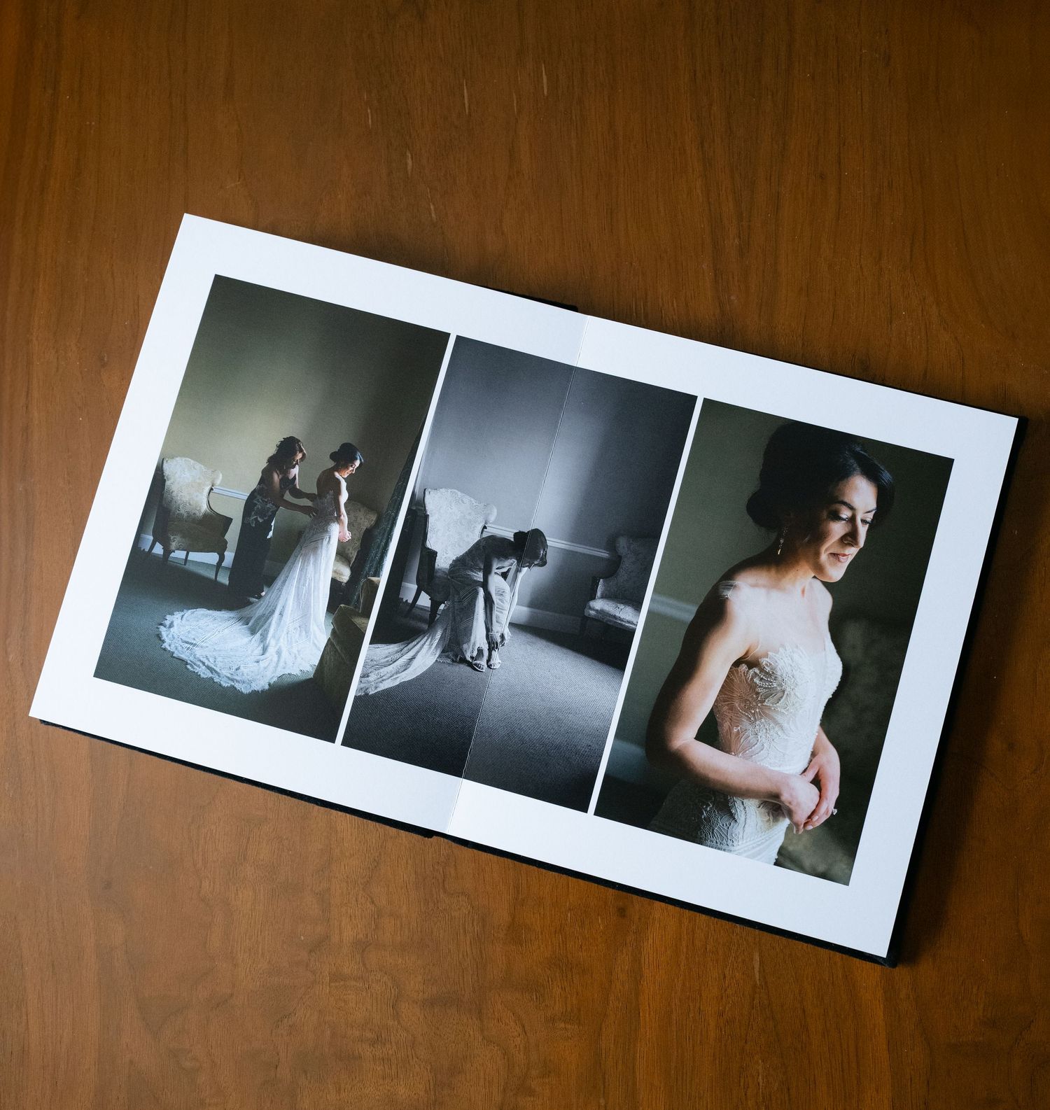 Black and white wedding album spreads laid out on dark wooden surface.