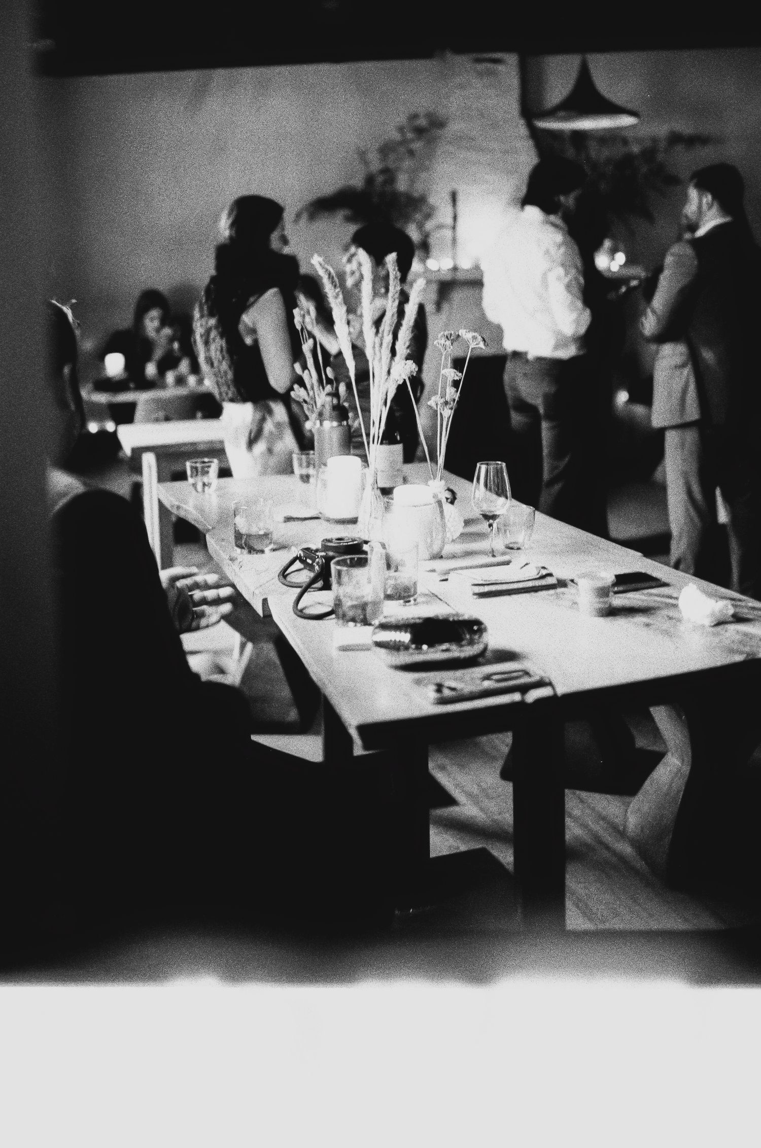 Elegant dinner table settings with glassware and place settings in dim lighting.