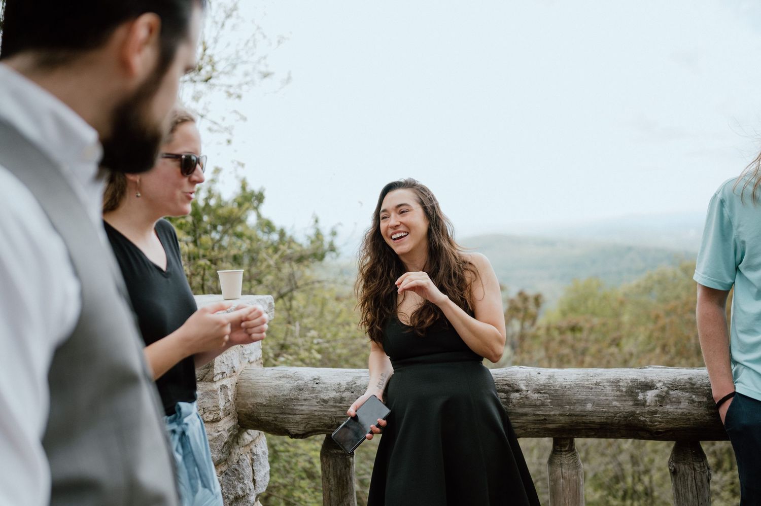 A casual gathering of people enjoying conversation on an outdoor mountain overlook.