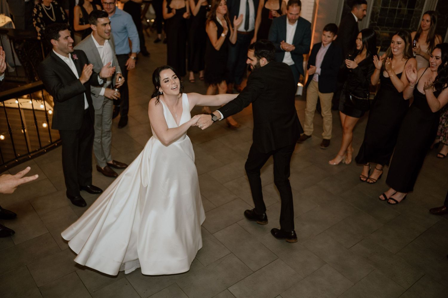 A couple shares their first dance at their wedding reception while guests watch from the sidelines.