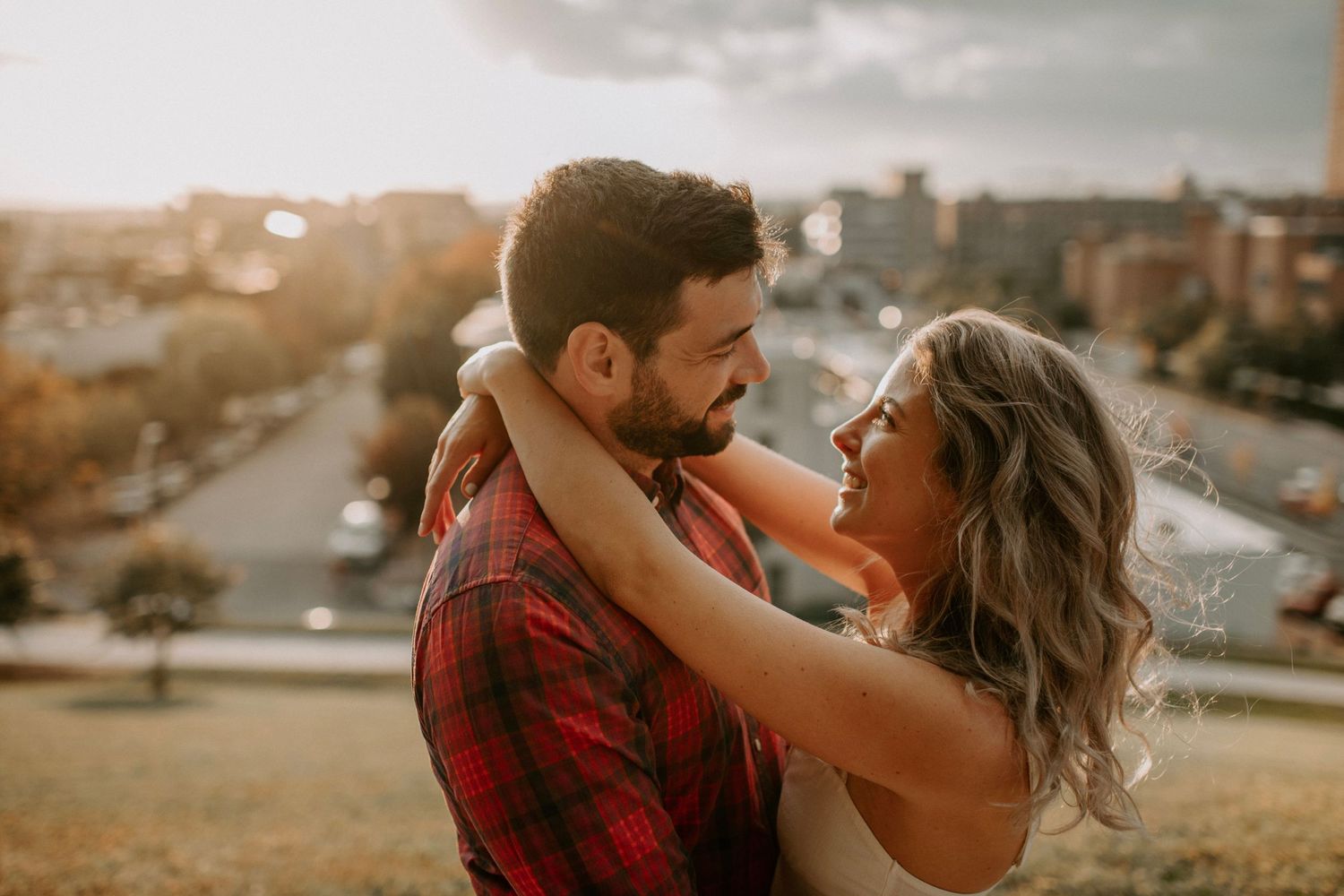 Joyful moment shared between couple laughing together on city rooftop at sunset.