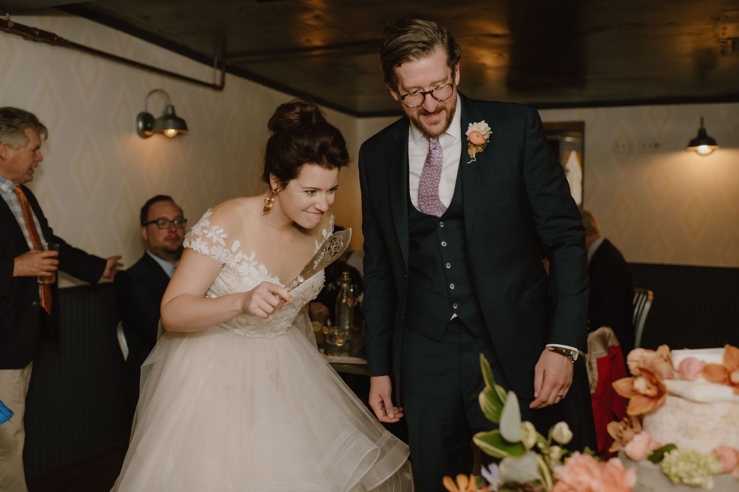 Newlyweds share a joyful moment looking at their wedding cake during the reception.