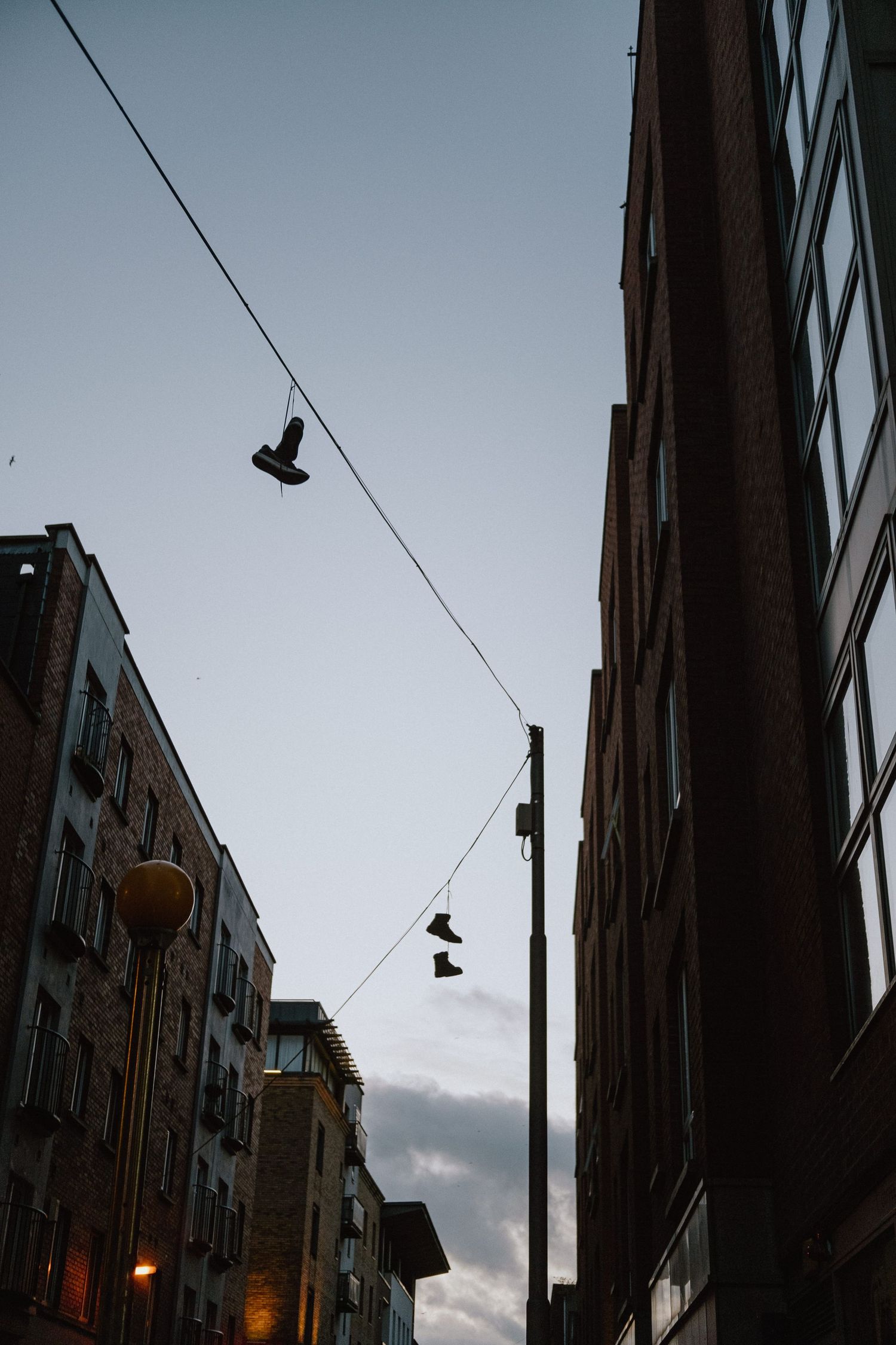 Shoes hanging on power lines between urban buildings at dusk.