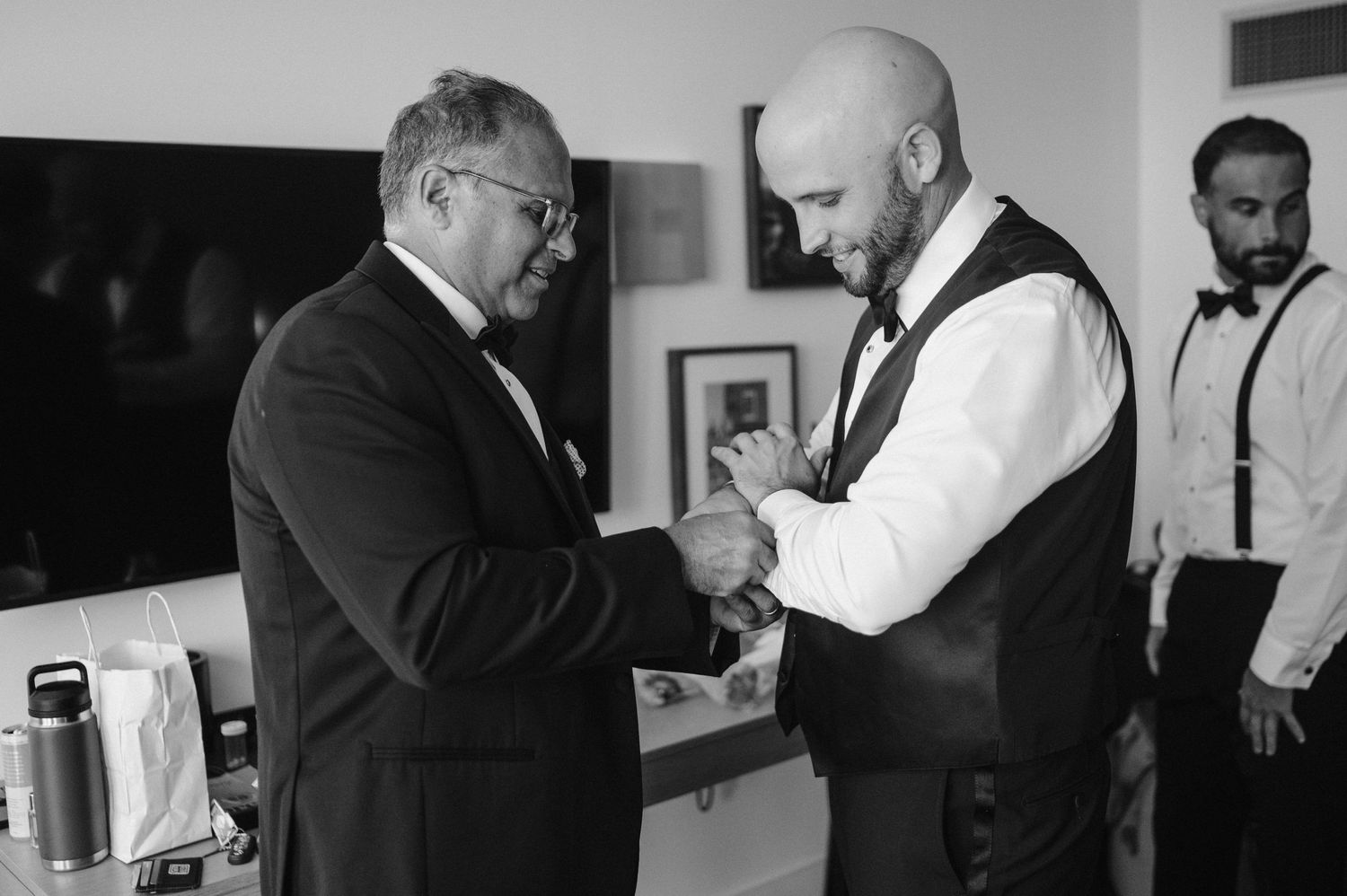Two men in formal attire shake hands in an indoor setting shown in black and white photography.