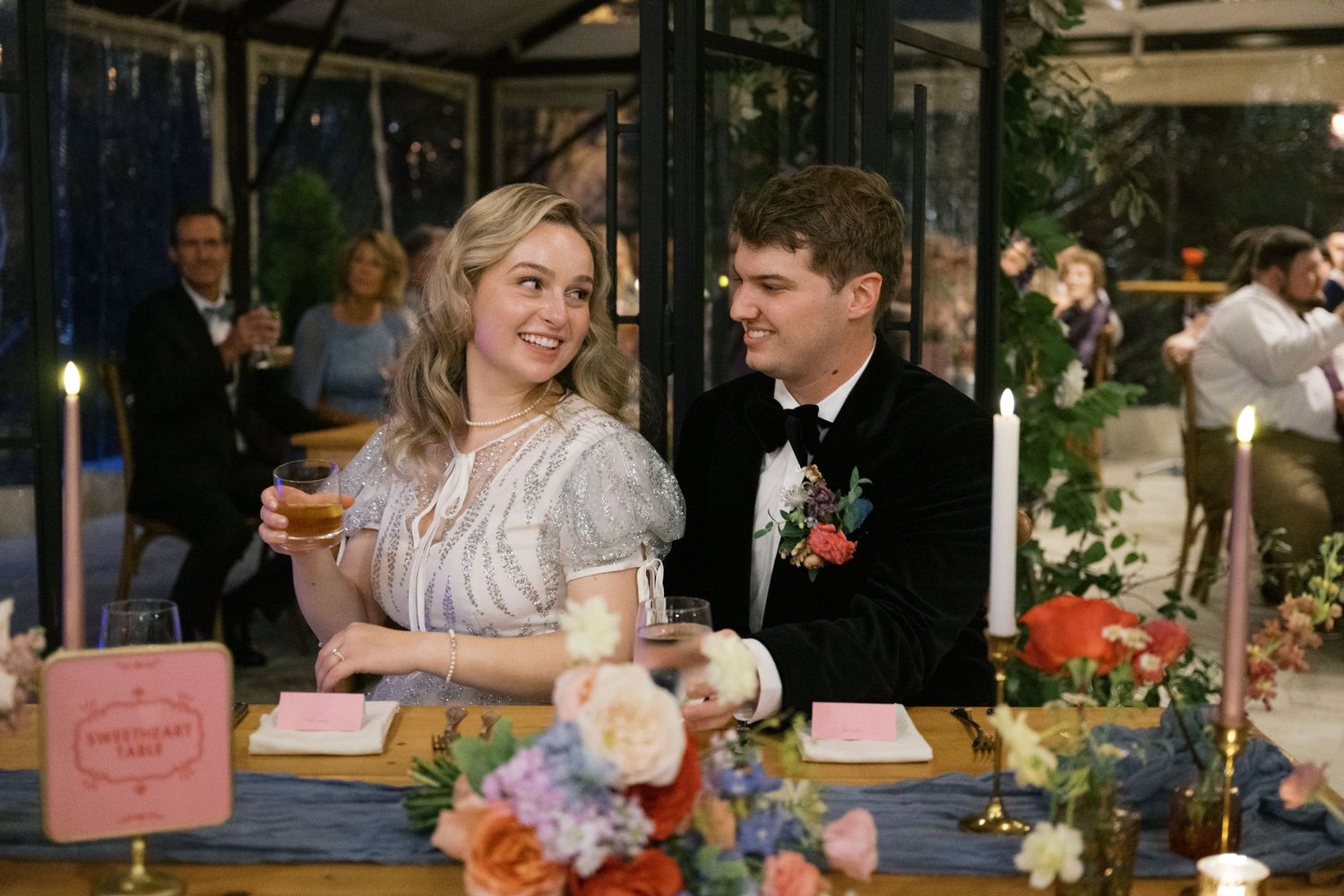 A couple shares a drink together at an elegant reception with flowers on the table.