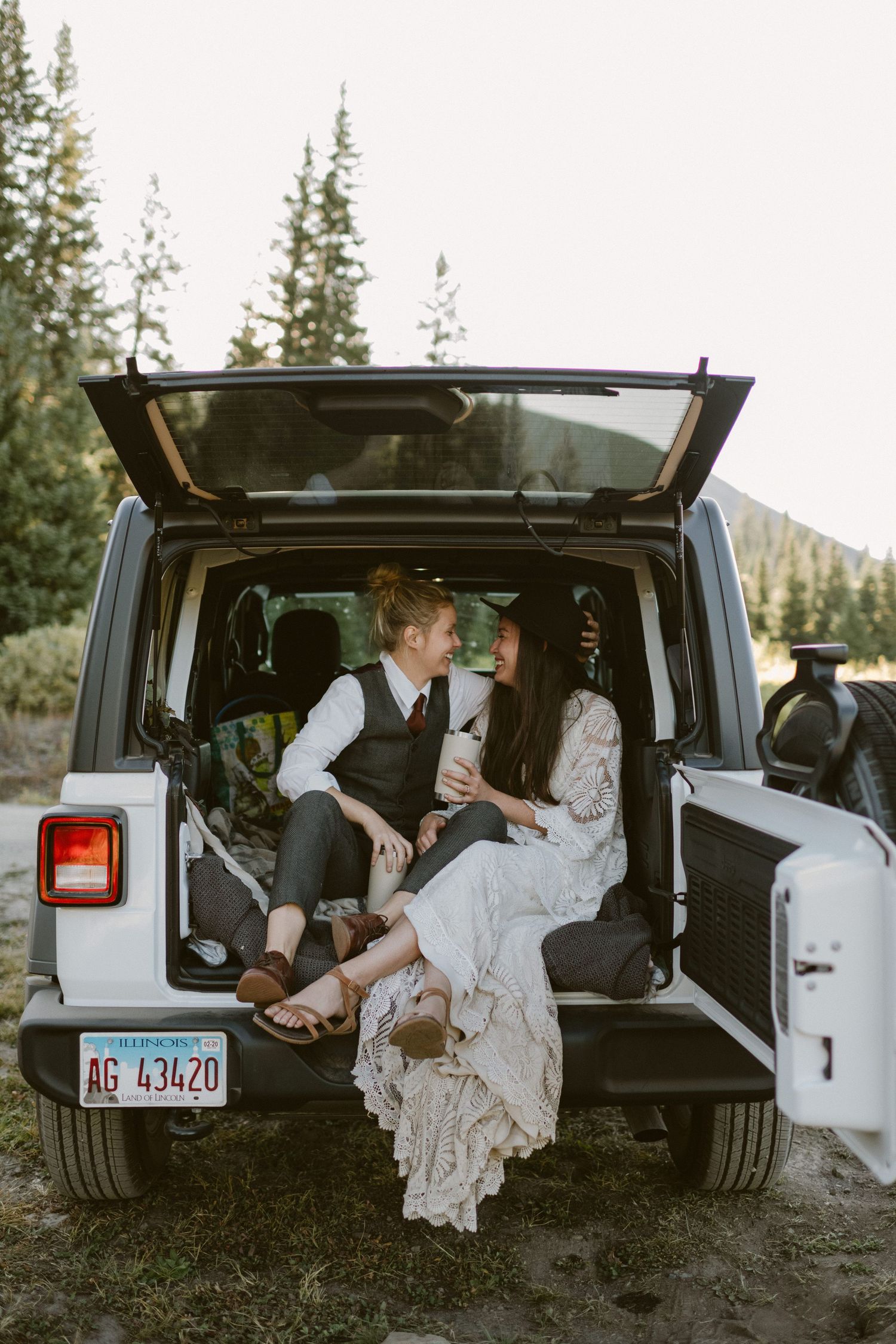 A couple sits together in the back of a white Jeep during their mountain elopement.