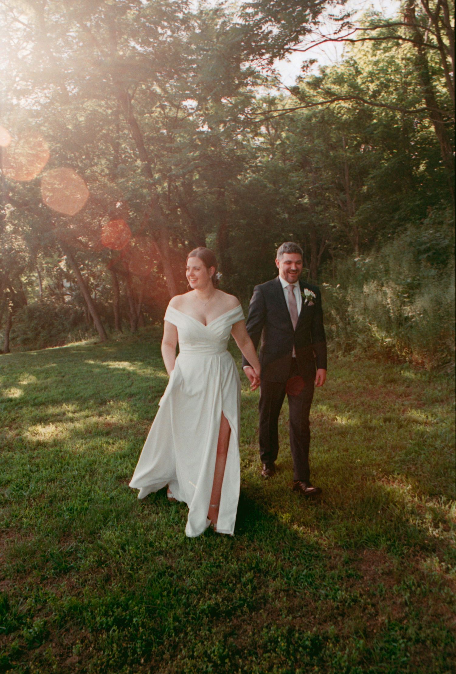 Wedding couple viewed from behind during outdoor sunset ceremony with decorative parasol.