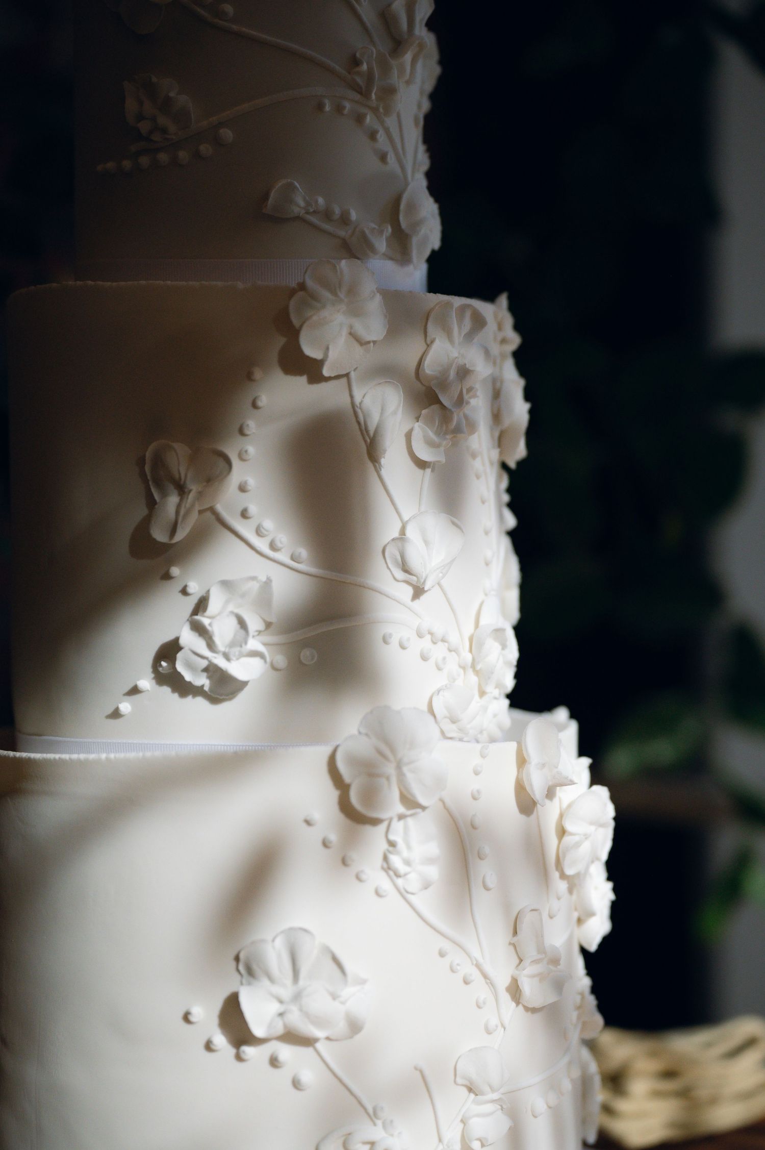 Elegant white wedding cake decorated with delicate sugar flowers and intricate details.