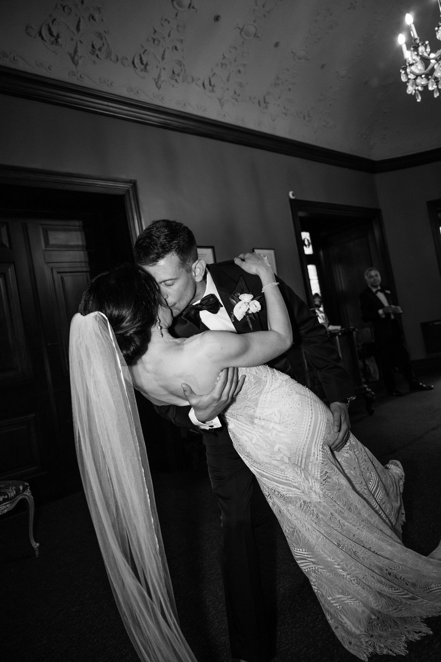 Dancing couple in formal attire captured in dramatic black and white lighting.