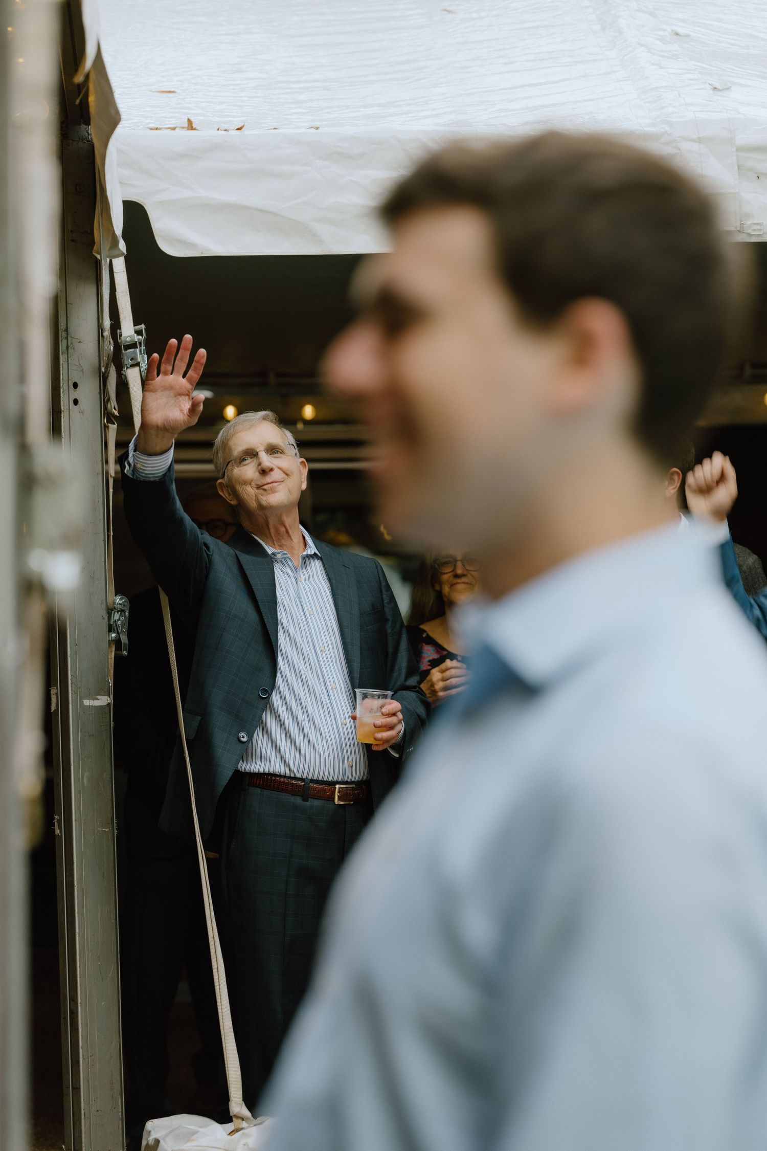 People mingling at a social event with one person waving.