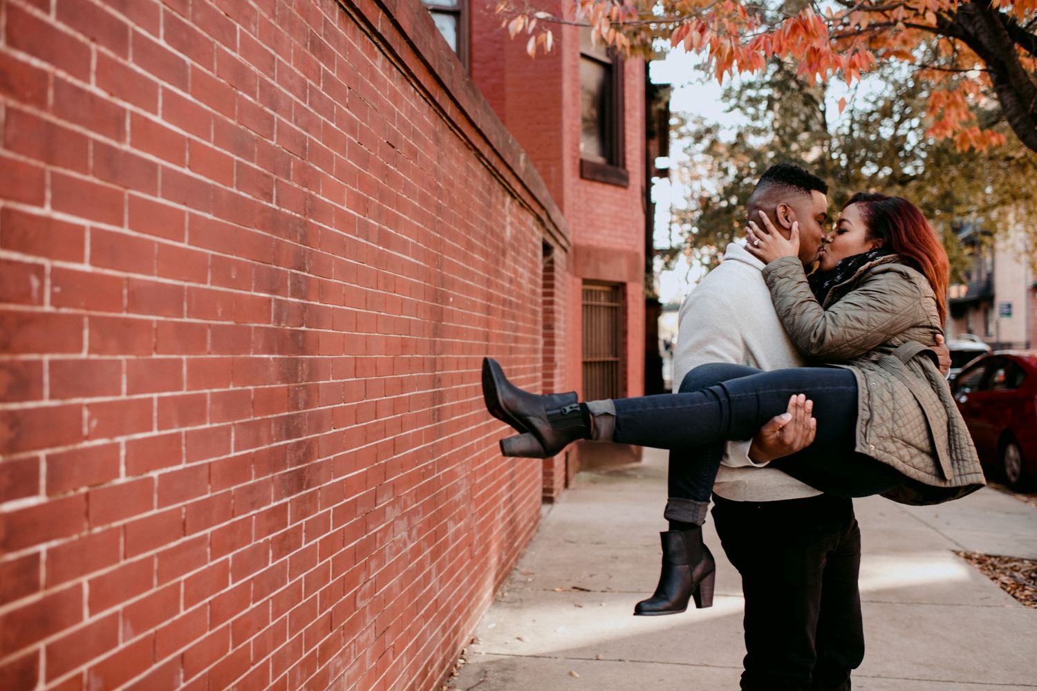 A romantic moment with someone being lifted and spun against a brick wall background.