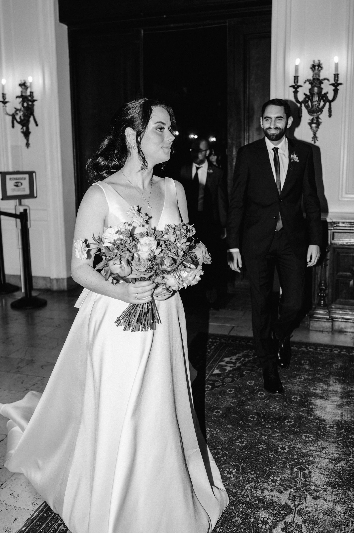Wedding portrait of a bride holding a bouquet while standing in an elegant room with vintage candelabras.