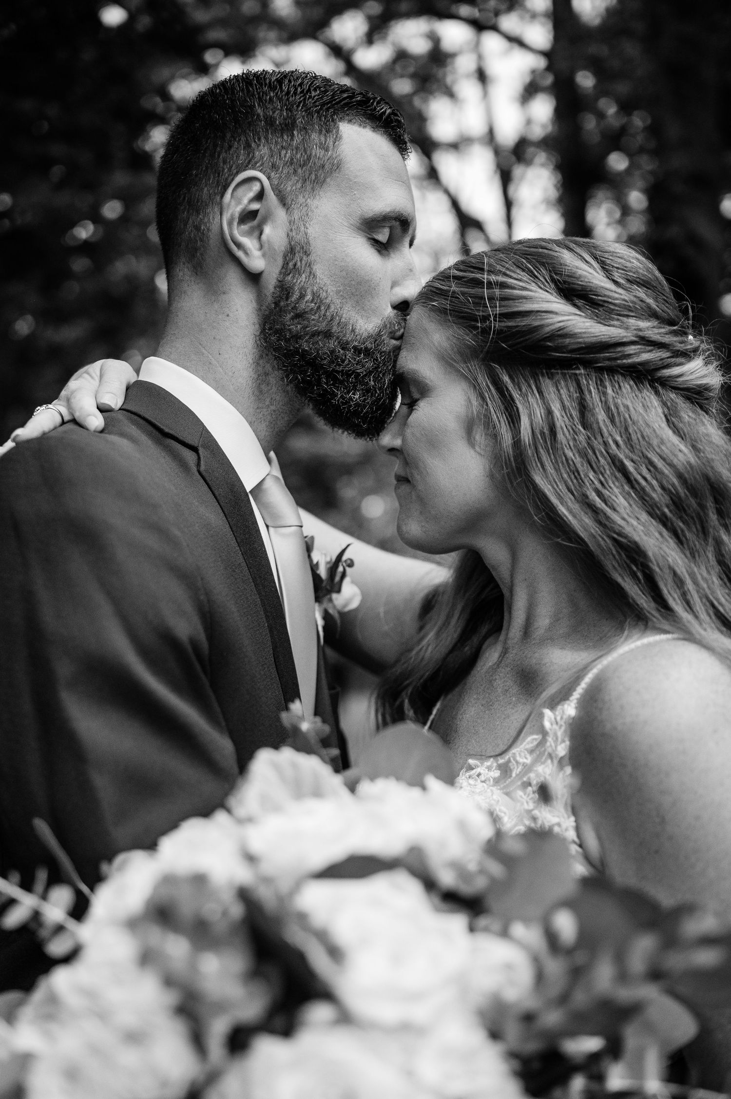 An intimate black and white portrait of newlyweds sharing a romantic moment.