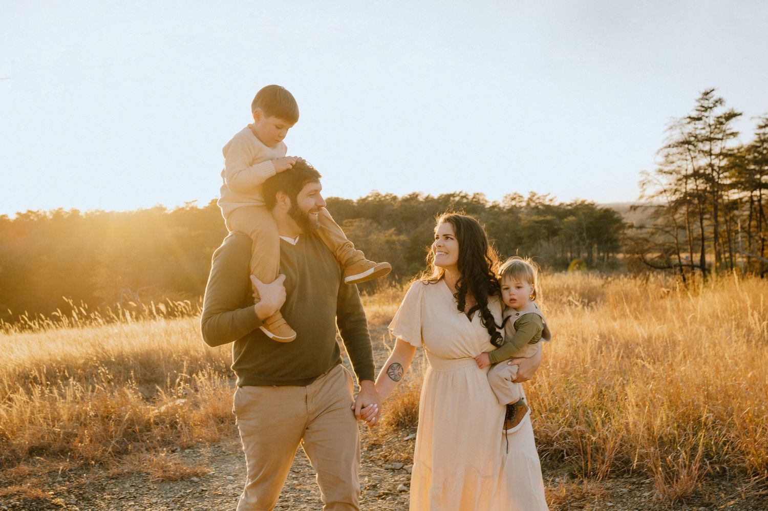 A family walks together through a golden field at sunset.