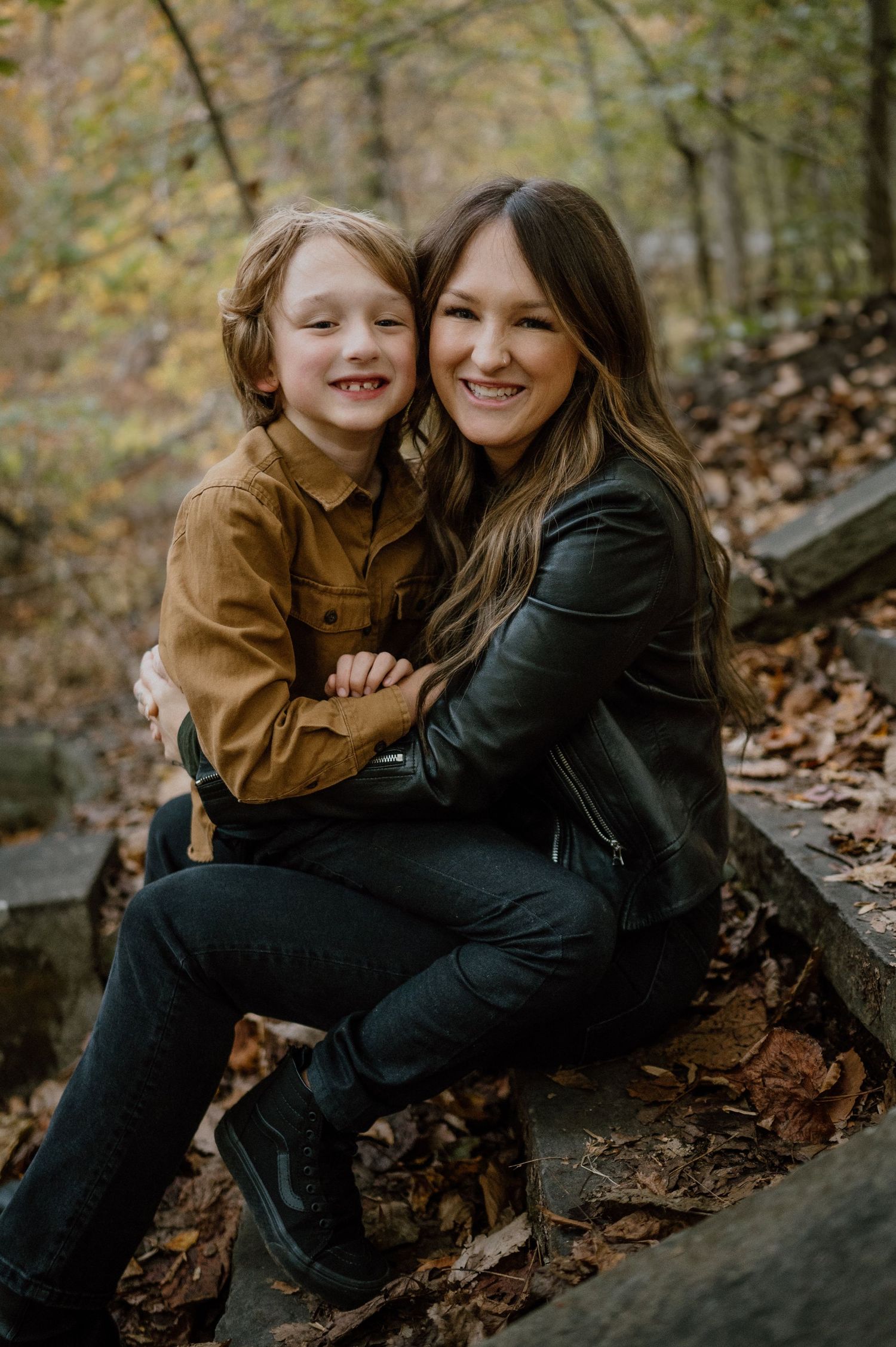 A heartwarming outdoor portrait showing genuine laughter and connection in a fall setting.