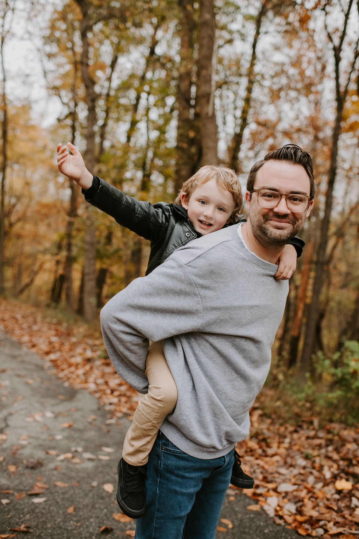 Playful piggyback ride on a forest path during autumn season.