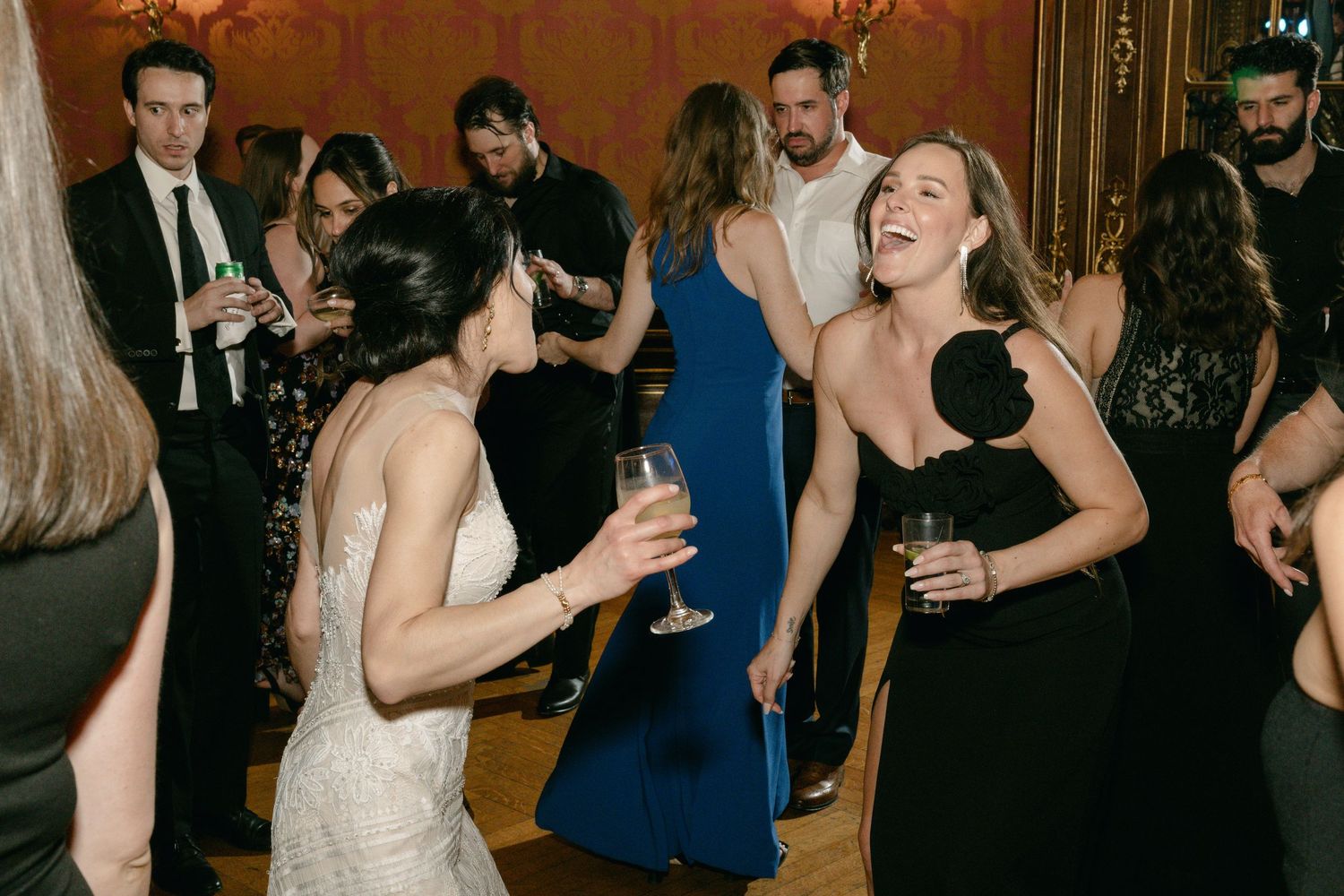 Guests in formal attire laughing and socializing at an elegant evening celebration.