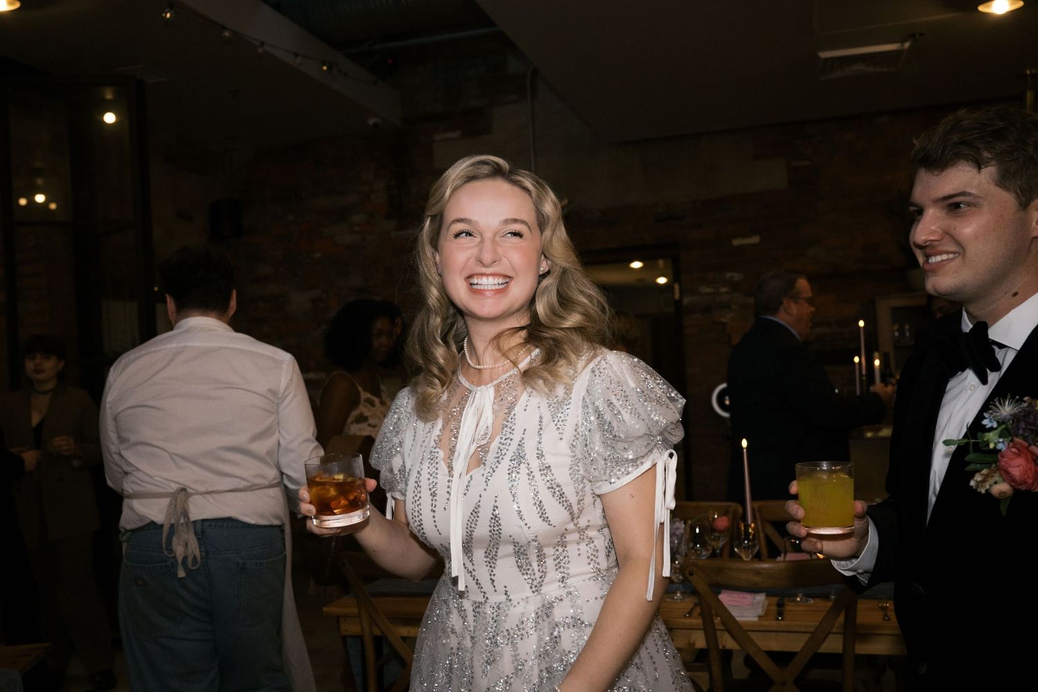 A bride in a vintage-style beaded dress enjoys a wedding reception.