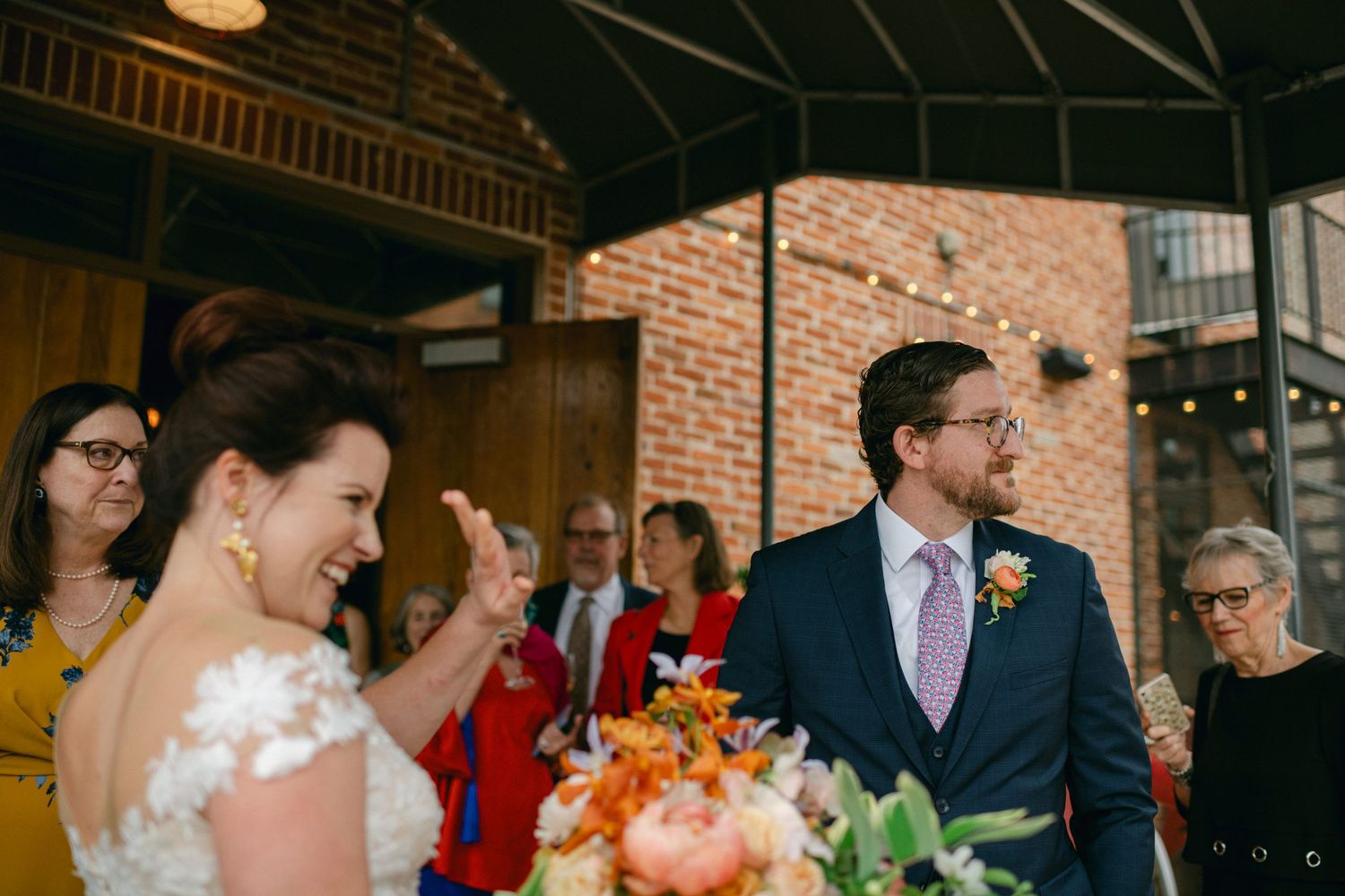 A candid wedding celebration moment inside a brick-walled venue with string lights.