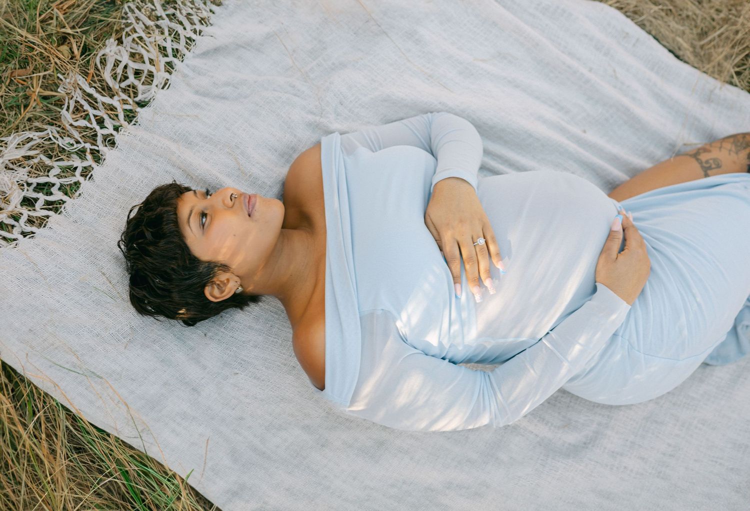 pregnant women lays on blanket holding baby bump