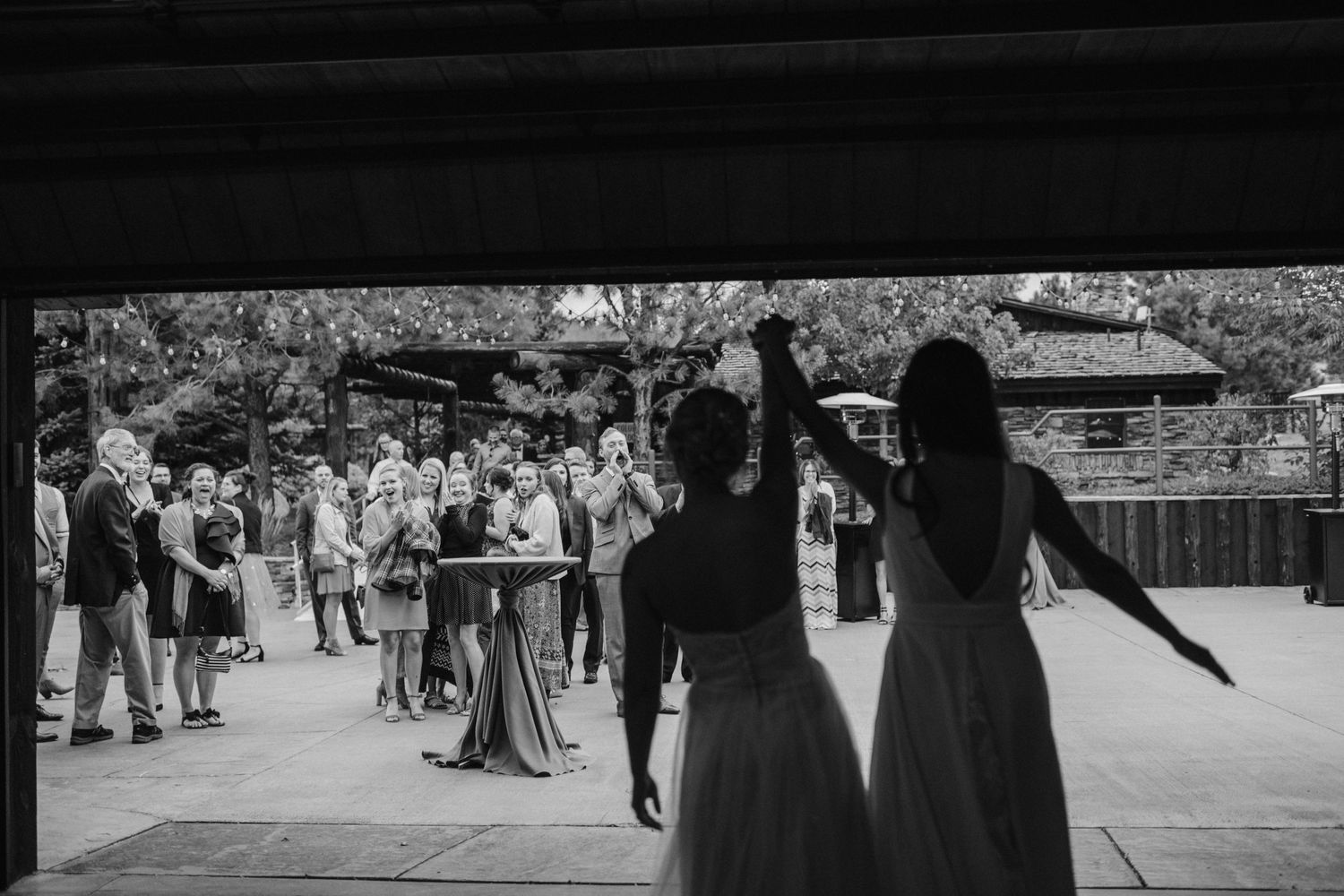 Two people in formal dresses dance together at an outdoor wedding reception.