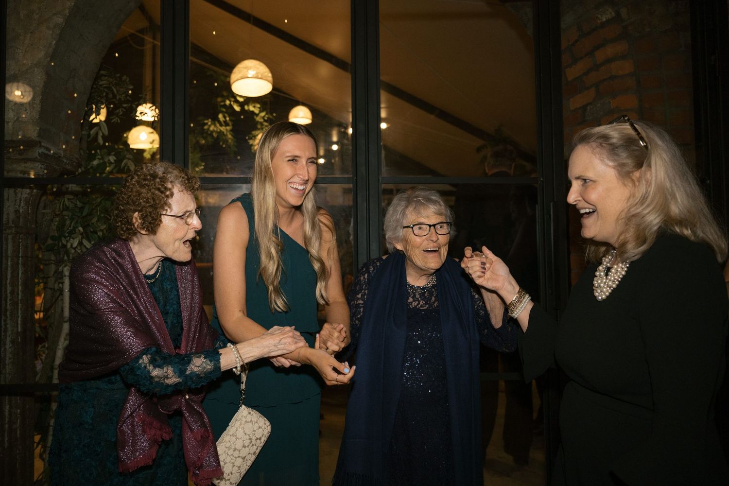 Group of people chatting and laughing in formal attire at an evening event.