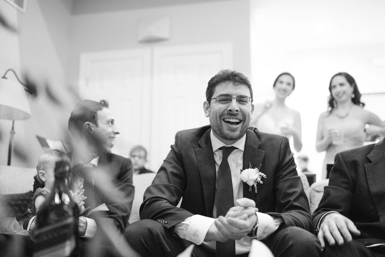 Candid black and white photo of guests laughing during a festive celebration.