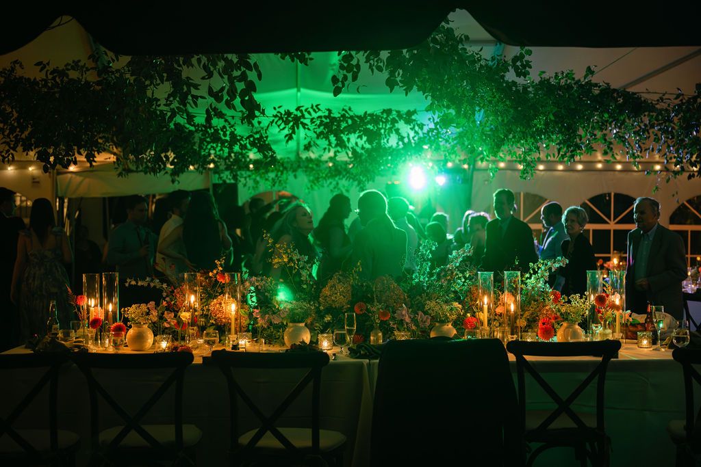 Wedding reception table setup with green lighting and floral decorations at night at Strong Mansion on Sugarloaf Mountain