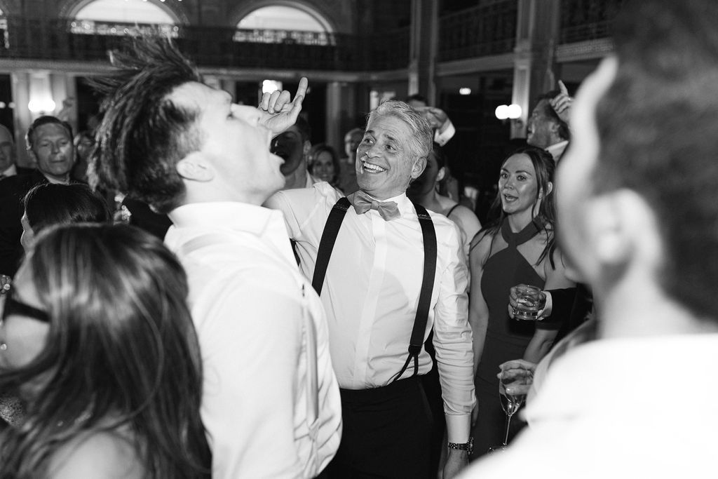 Wedding reception guests dancing and celebrating in formal attire.